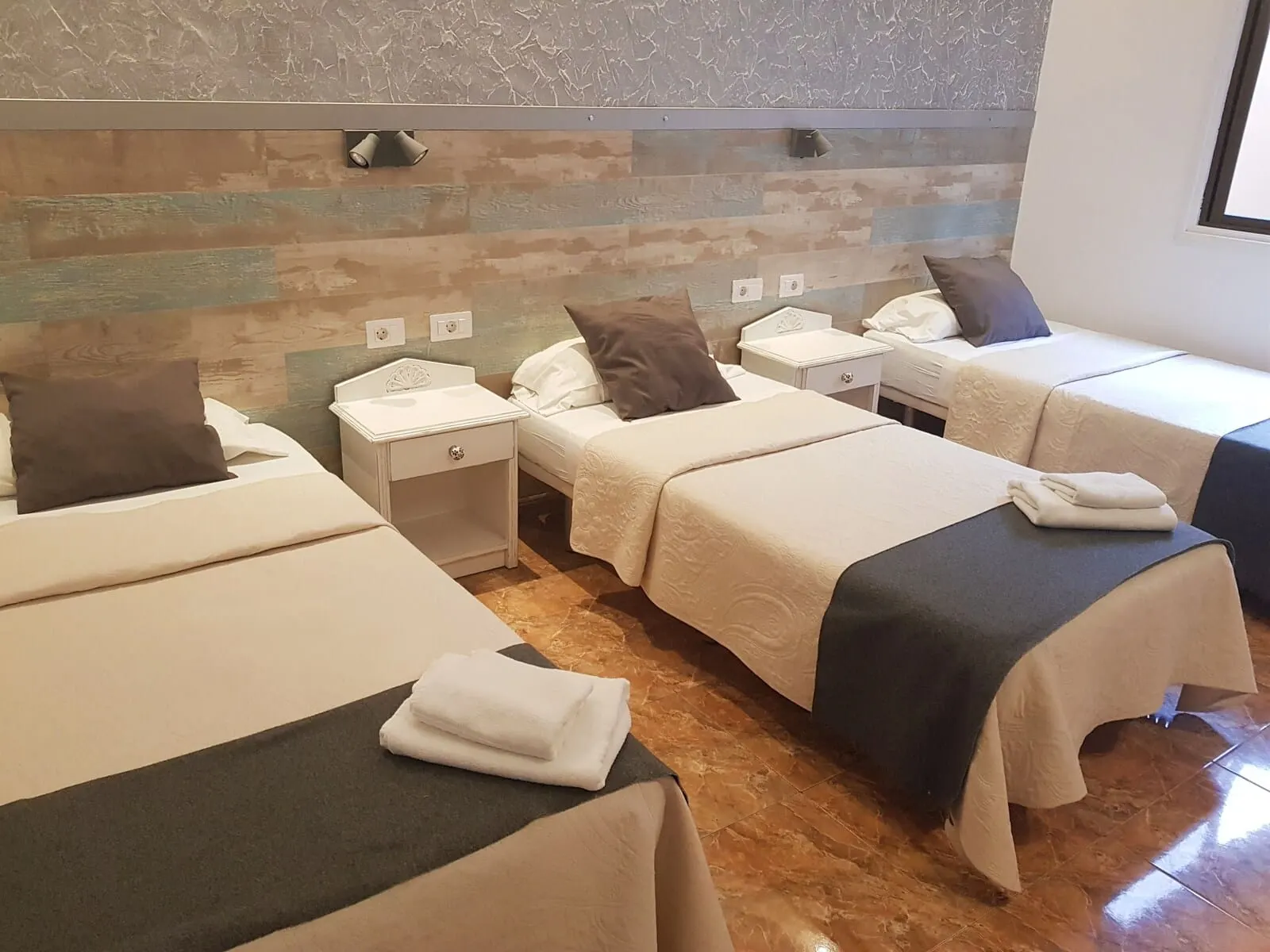 Nuevo Hotel Horizonte: A hotel room with two beds, a nightstand, a small table