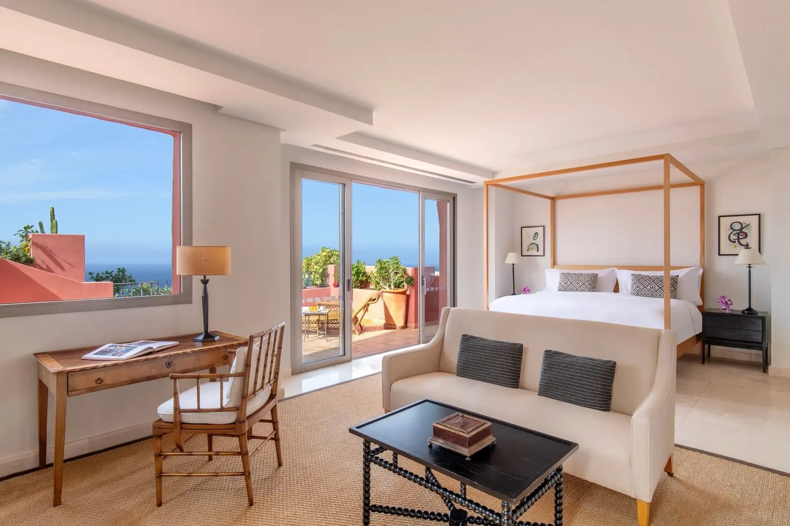 The Ritz-Carlton Tenerife, Abama: A hotel room with a large bed, a desk, a chair, a coffee table, and a view of the ocean