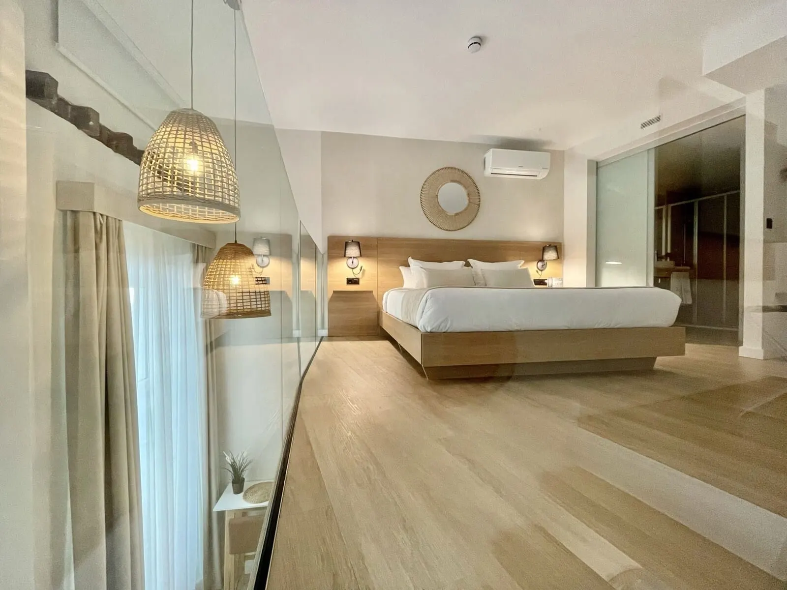 Hi Suites: A modern bedroom with a large bed, bedside lamps, a wall-mounted air conditioner