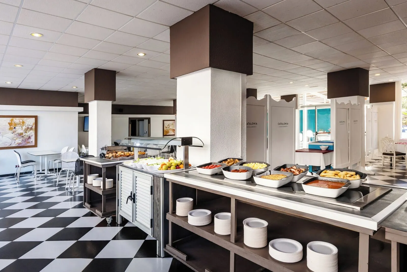 Catalonia Punta del Rey: A buffet area with various food stations, a check-in counter, and a check-out counter