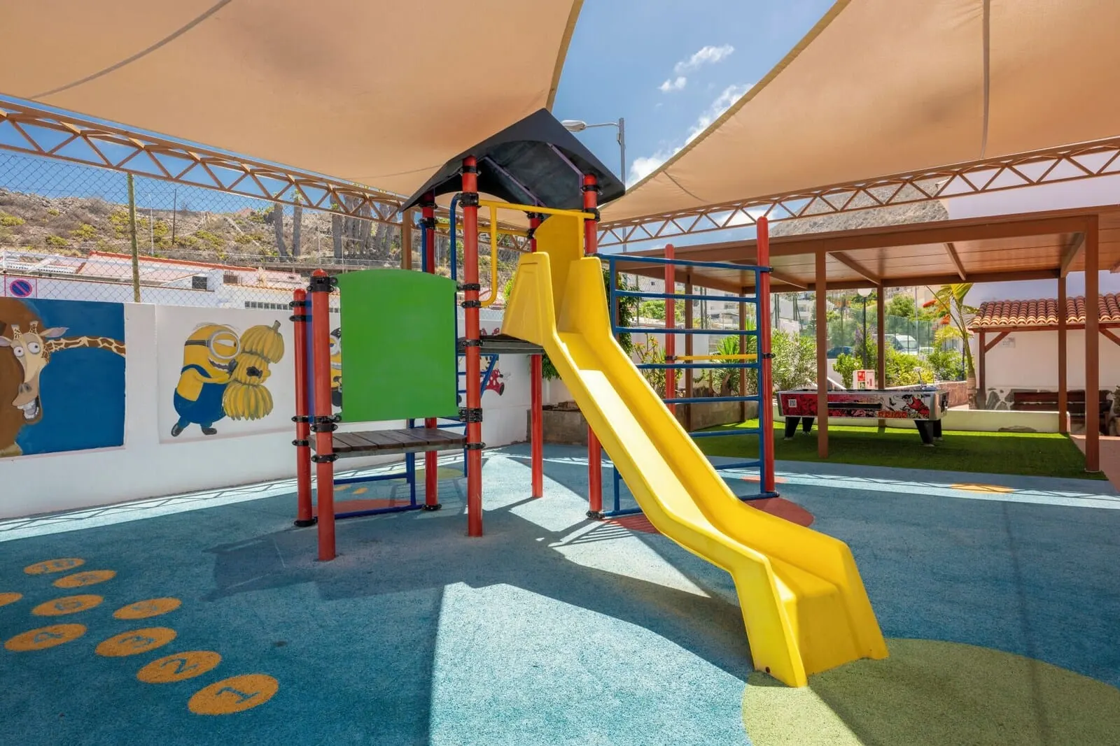 Ona Los Claveles: A playground with a yellow slide, climbing structures