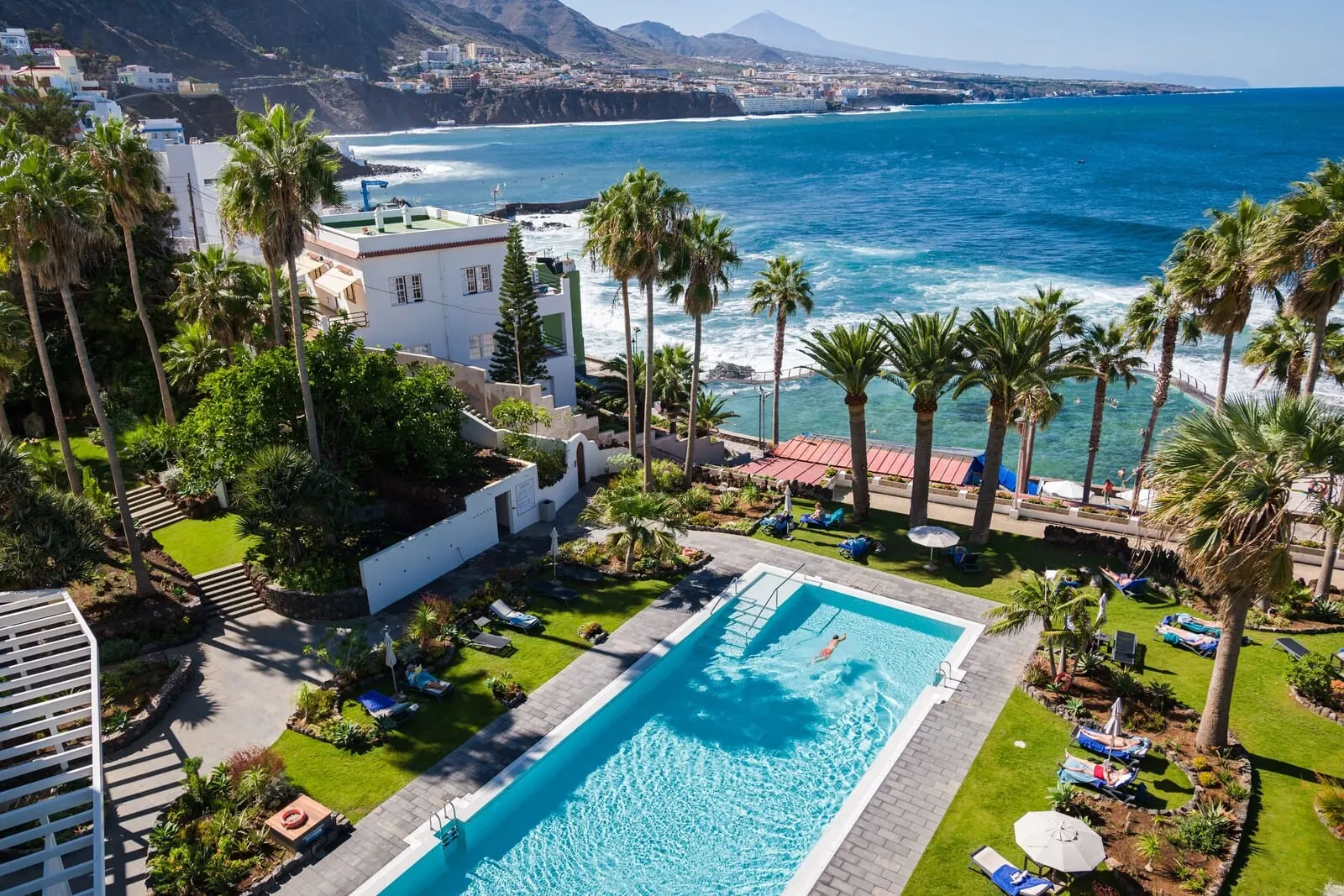 Océano Health Spa Hotel: A pool area with a view of the ocean, surrounded by palm trees and lounge chairs