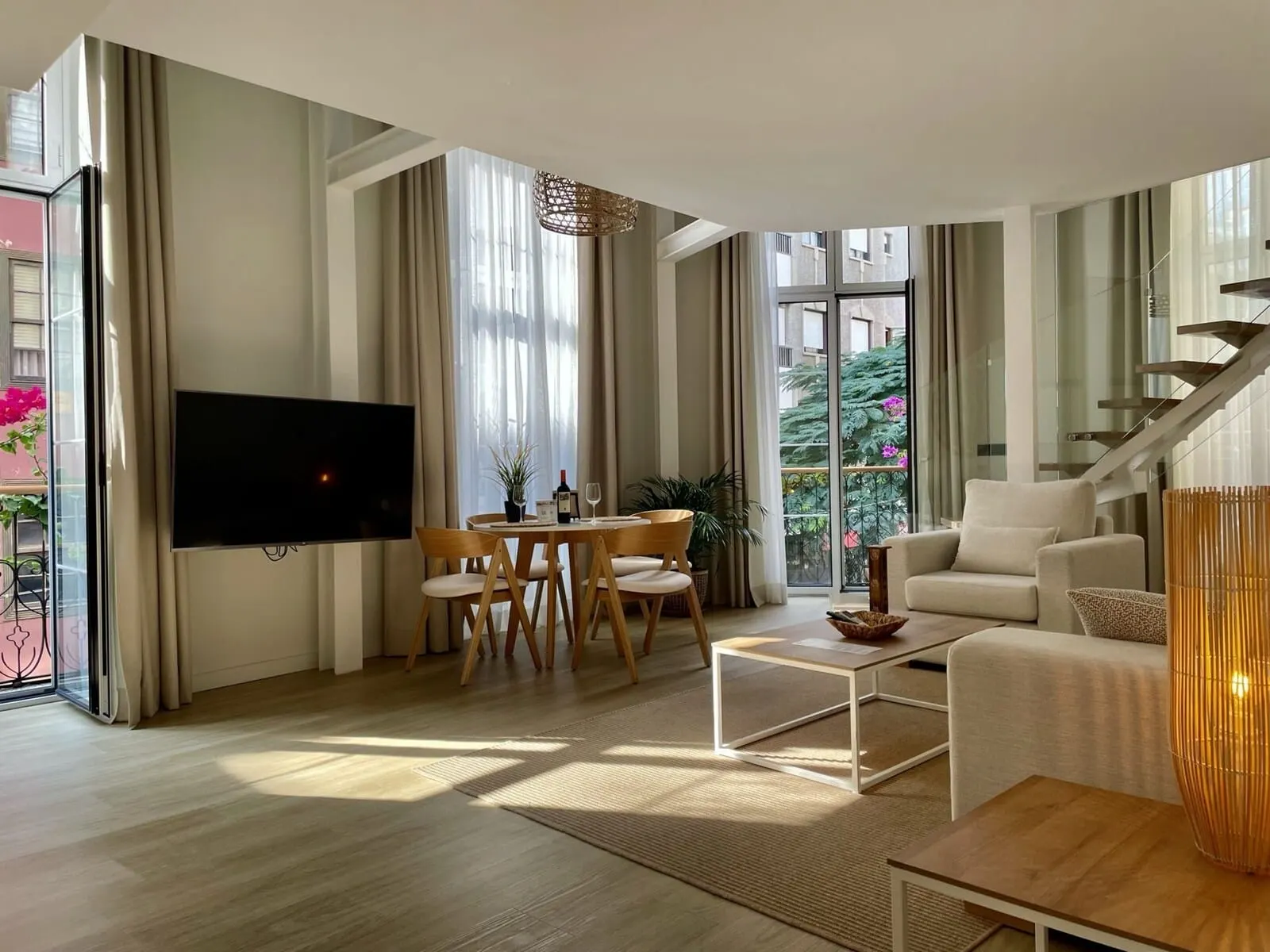 Hi Suites: A modern living room with a flat-screen TV, a dining area with a table and chairs
