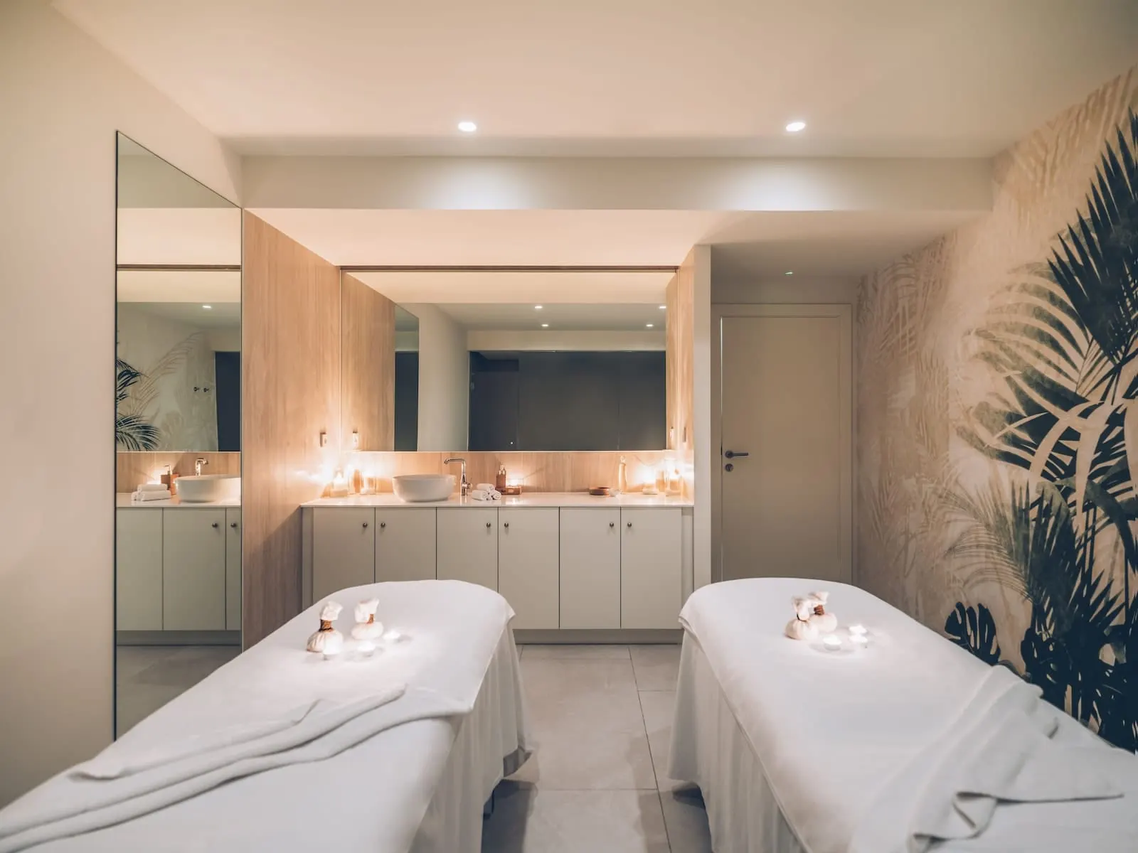 Iberostar Selection Sábila: A modern spa room with two treatment beds, a large mirror, and a large plant