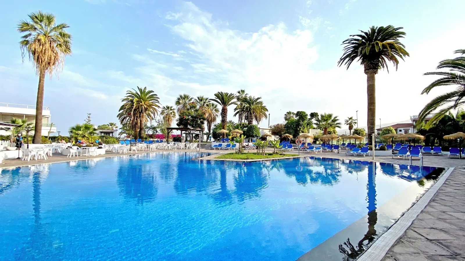 BLUESEA Interpalace: A large outdoor swimming pool surrounded by palm trees and blue lounge chairs