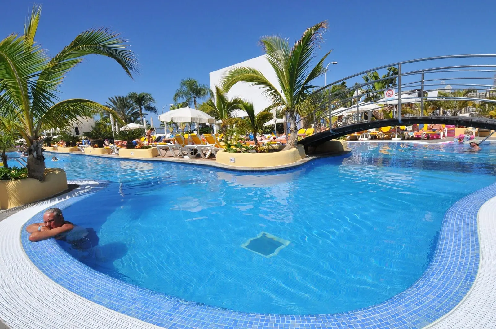 Paradise Park Fun Lifestyle Hotel: A swimming pool with lounge chairs, palm trees, and a bridge
