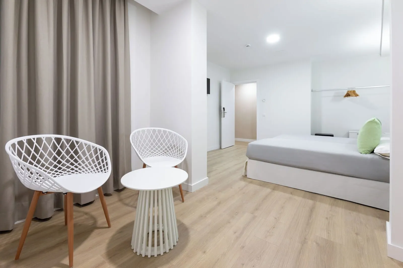 Hotel Boutique HC Maga: A modern hotel room with a wooden floor, a grey sofa, two white chairs