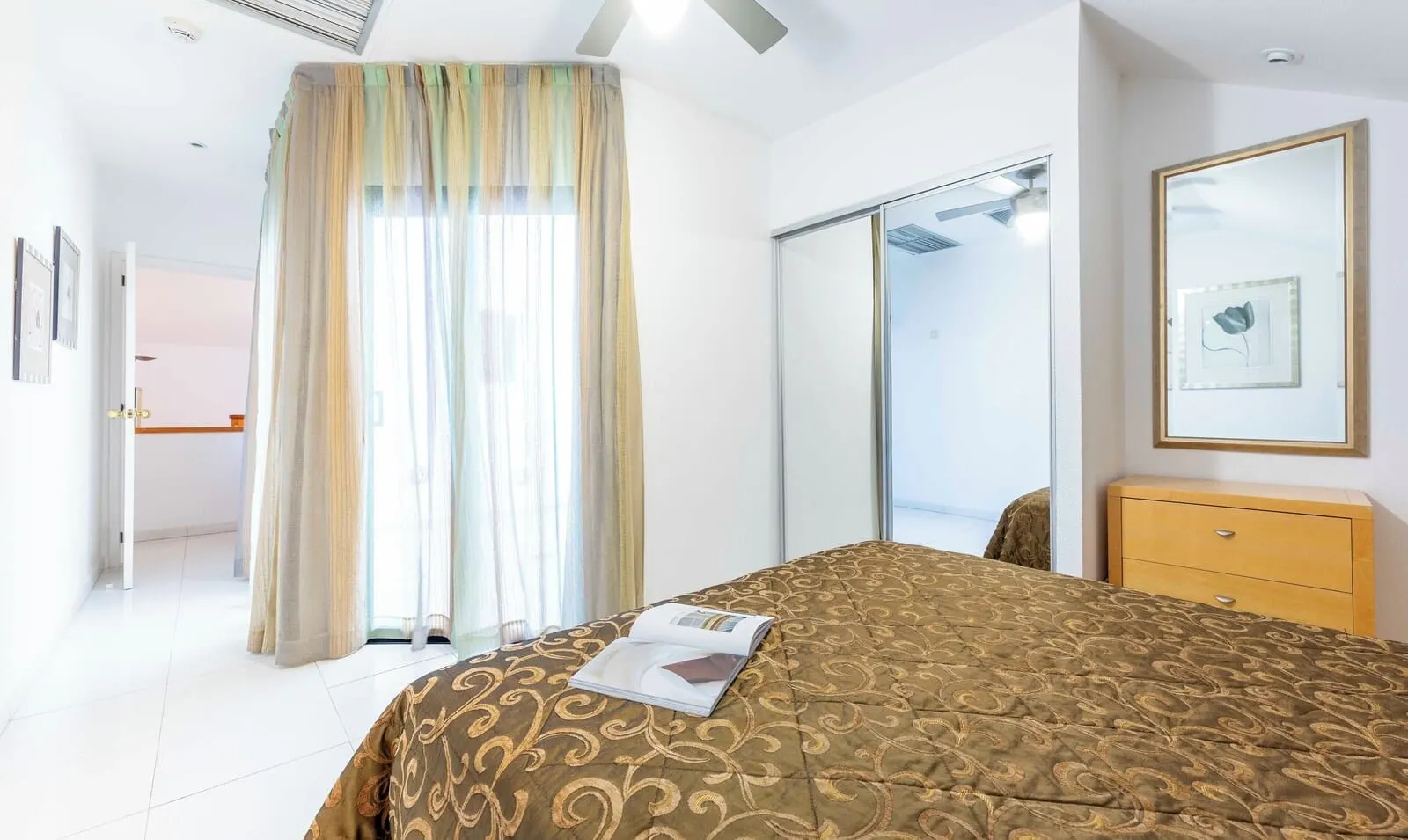Ona Hollywood Mirage: A hotel room with a bed, a dresser, a mirror, and a door leading to a balcony