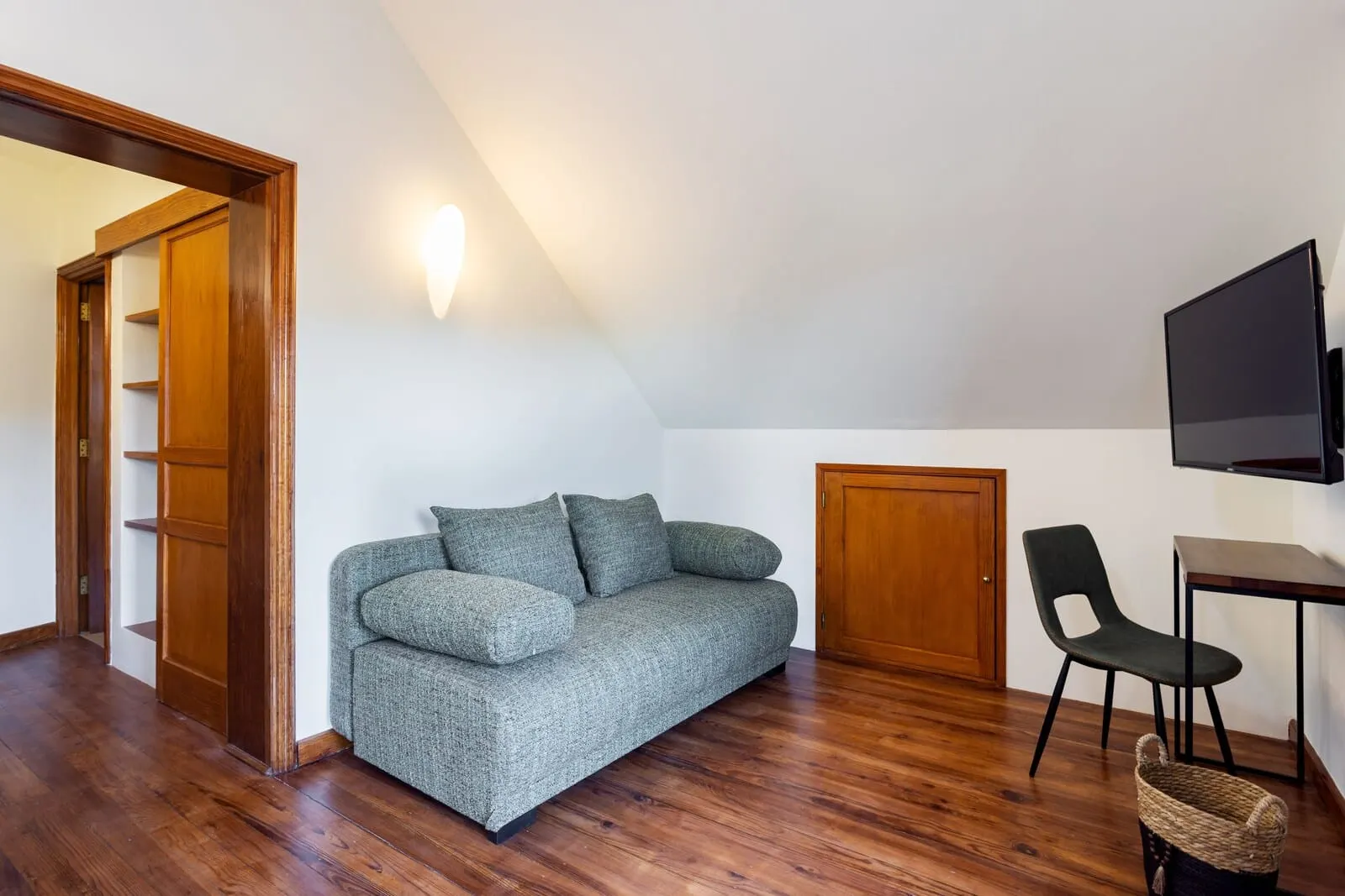 Hotel Alta Montaña: A room with a grey sofa, a wooden door, a TV mounted on the wall, and a chair