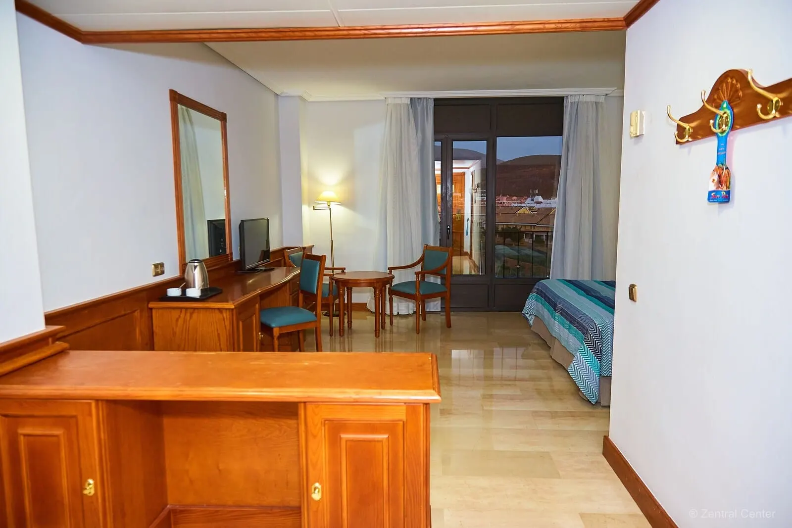 Hotel Zentral Center: A hotel room with a wooden desk, two chairs, a bed with a striped bedspread