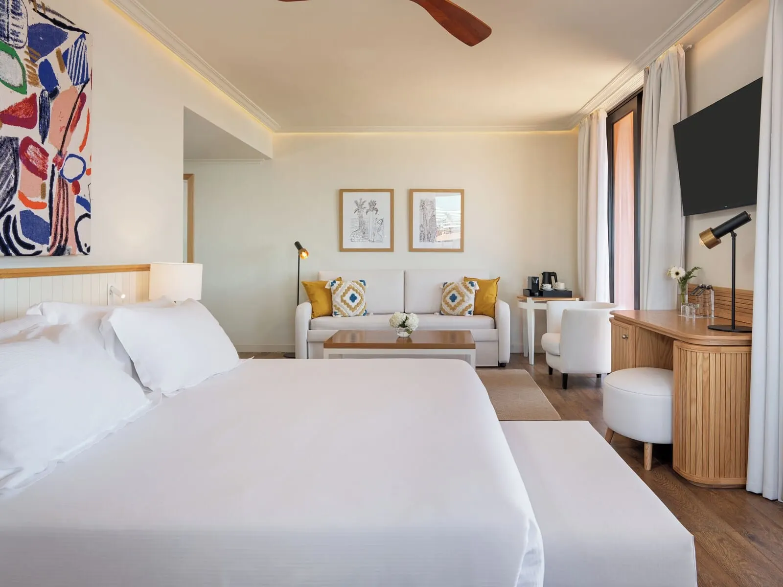 H10 Costa Adeje Palace: A hotel room with a large bed, a sofa, a desk, and a TV