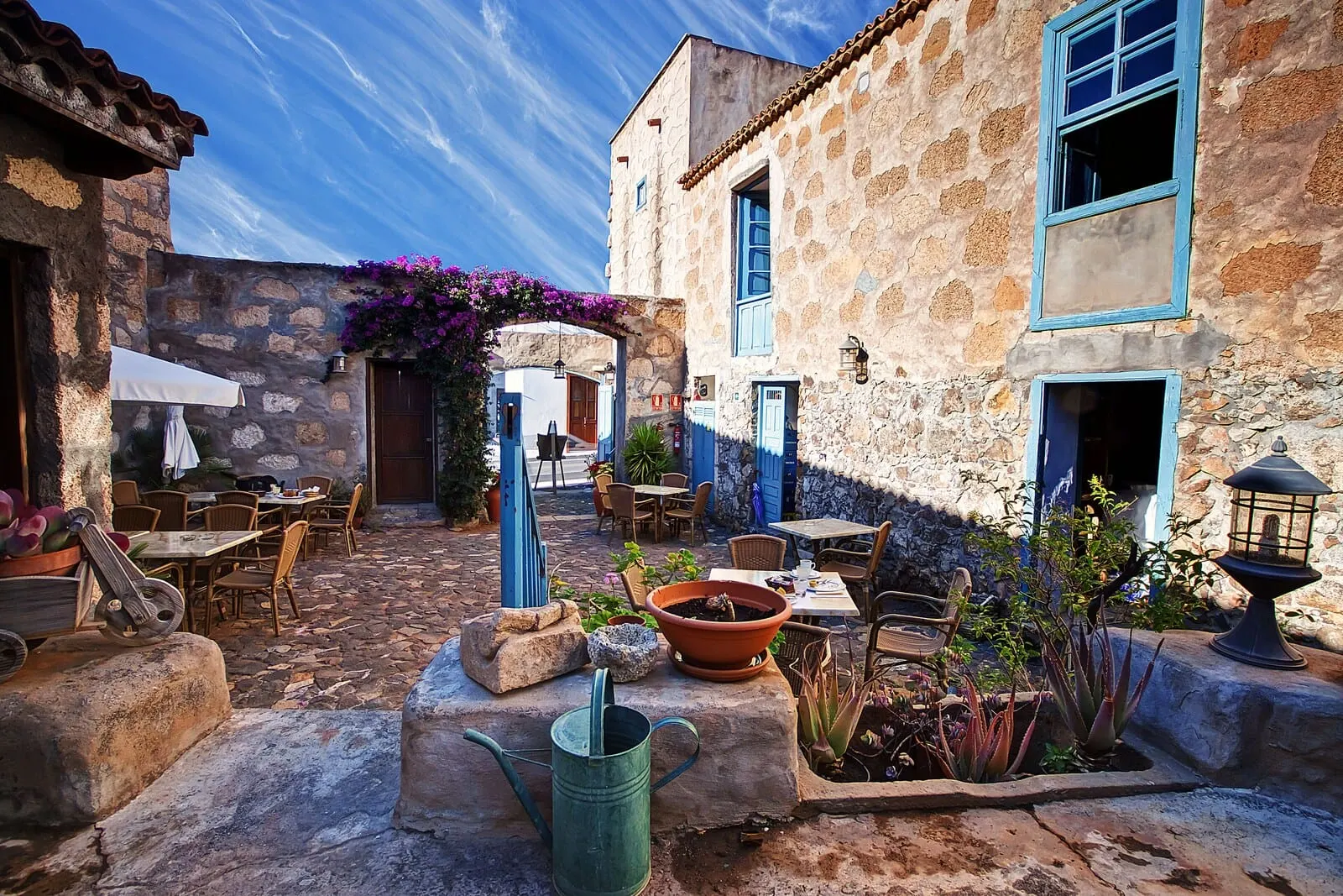 Hotel Cuatro Esquinas: A courtyard with stone buildings, outdoor seating, and potted plants