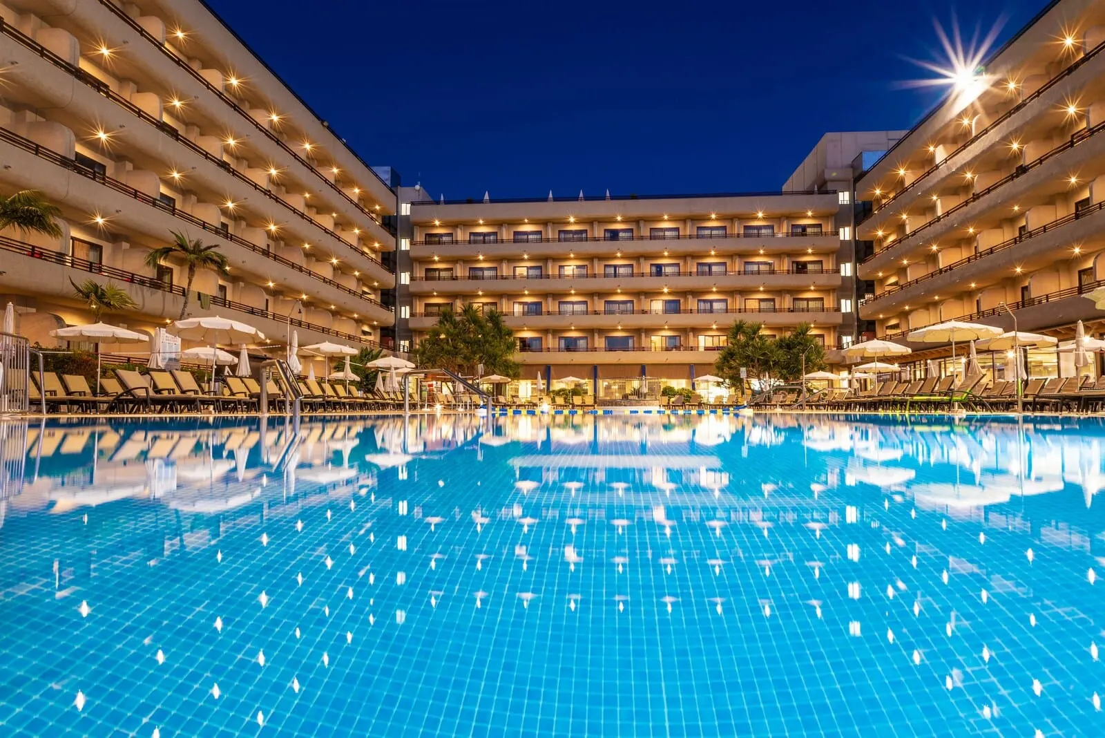 GF Fañabé: A hotel with a large swimming pool, multiple balconies, and outdoor seating areas