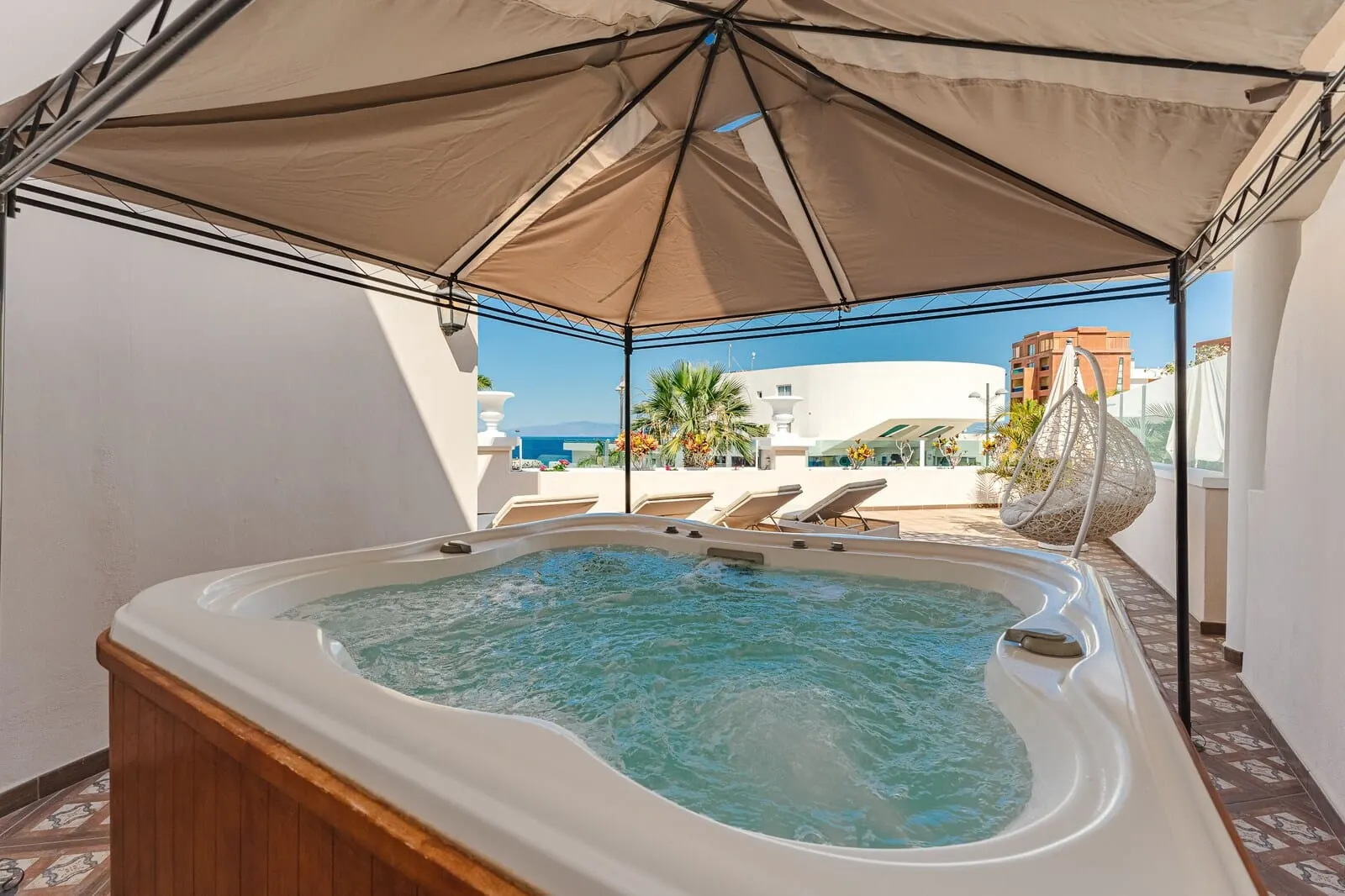 Flamingo Suites Boutique Hotel: A hot tub under a canopy with a view of the sea and buildings