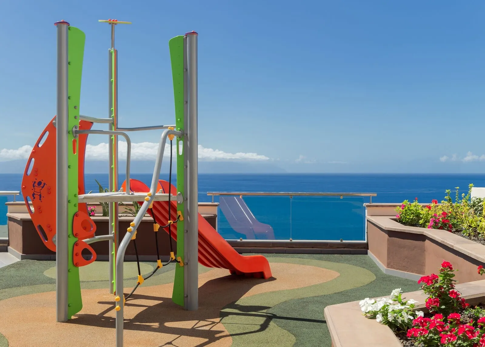 Royal Sun Resort: A playground with a slide and climbing structure, overlooking a pool and ocean view
