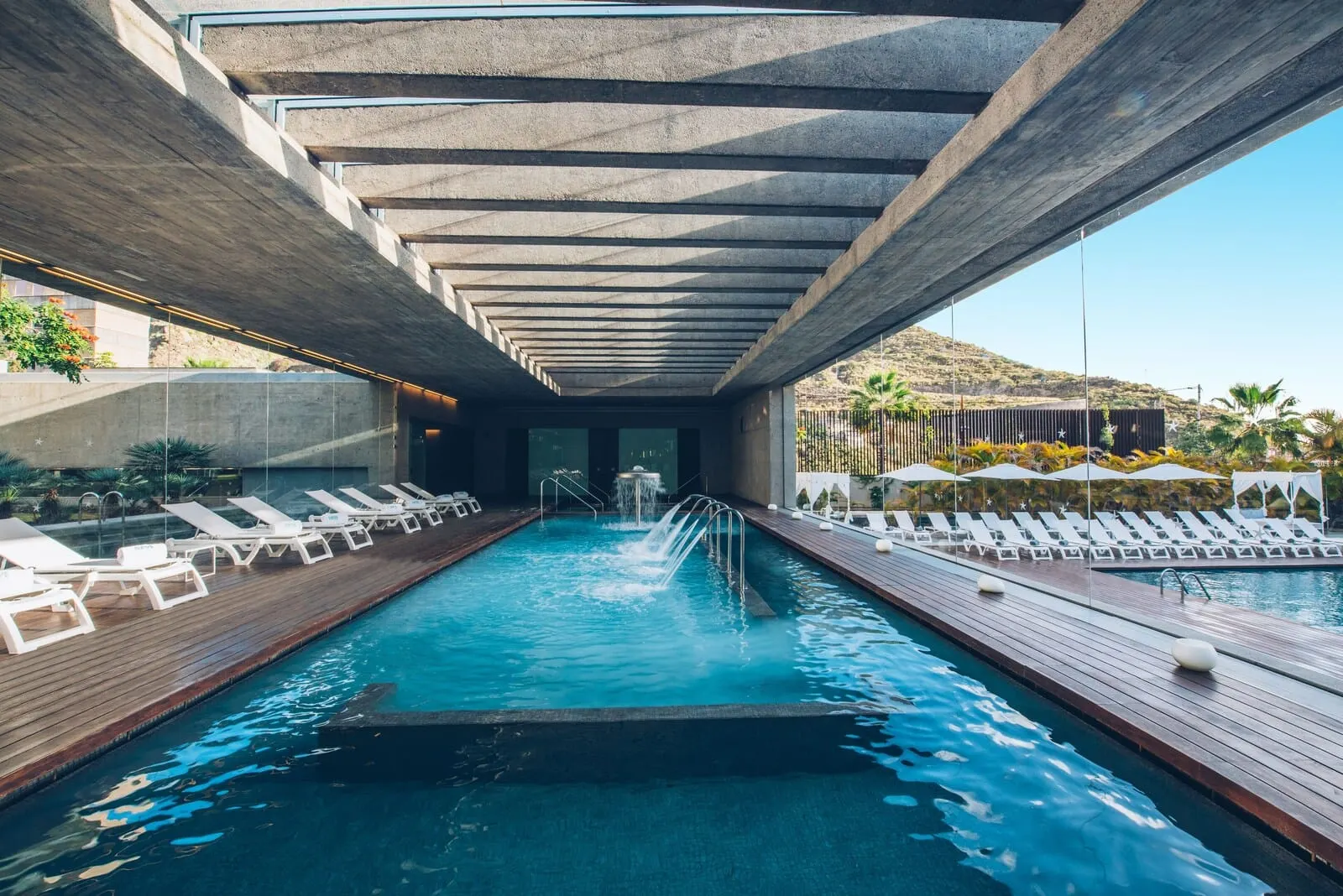 Iberostar Heritage Grand Mencey: A swimming pool with a wooden deck, lounge chairs, and a concrete ceiling structure