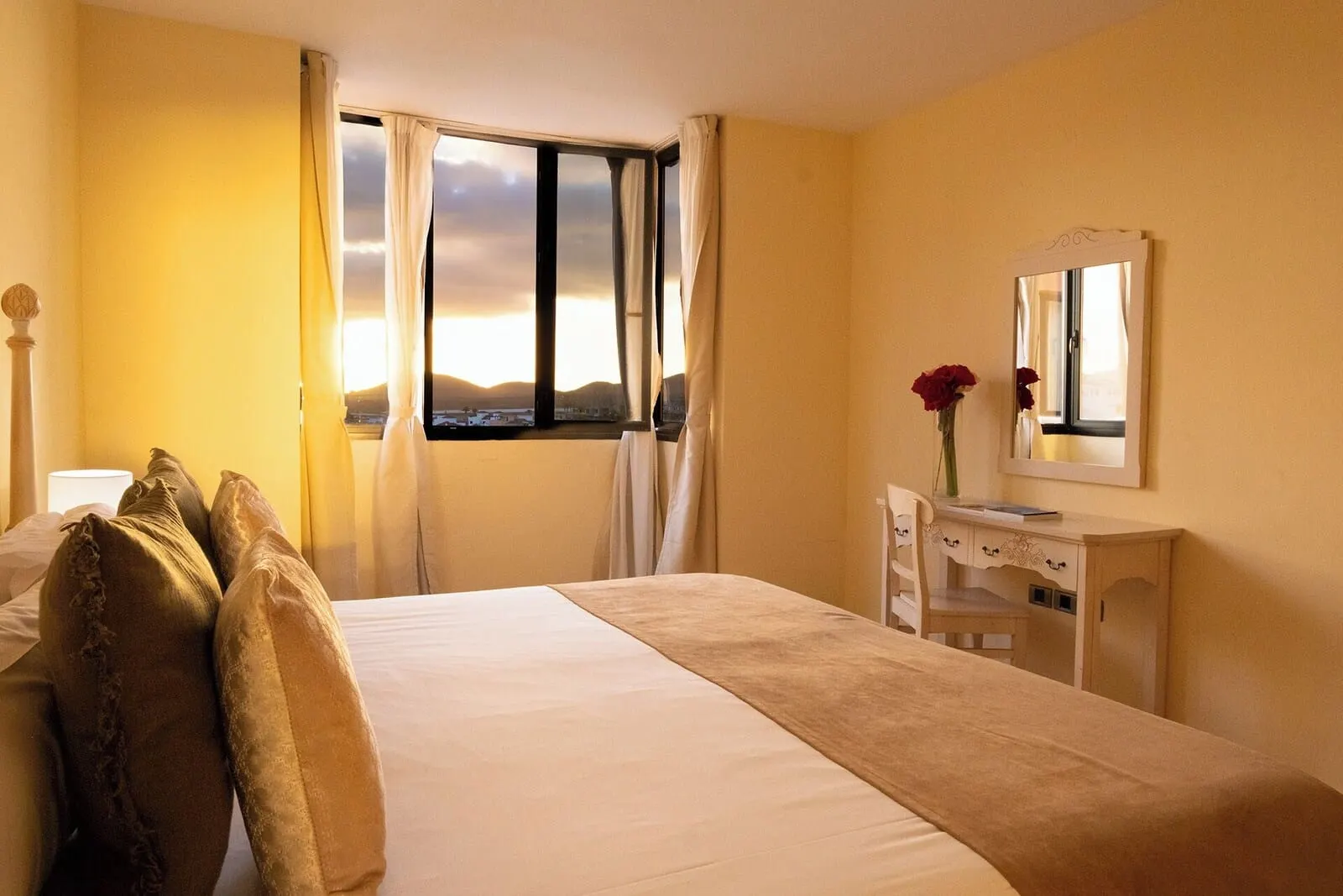 Grand Muthu Golf Plaza Hotel & Spa: A hotel room with a bed, a desk, a mirror, and a window with curtains
