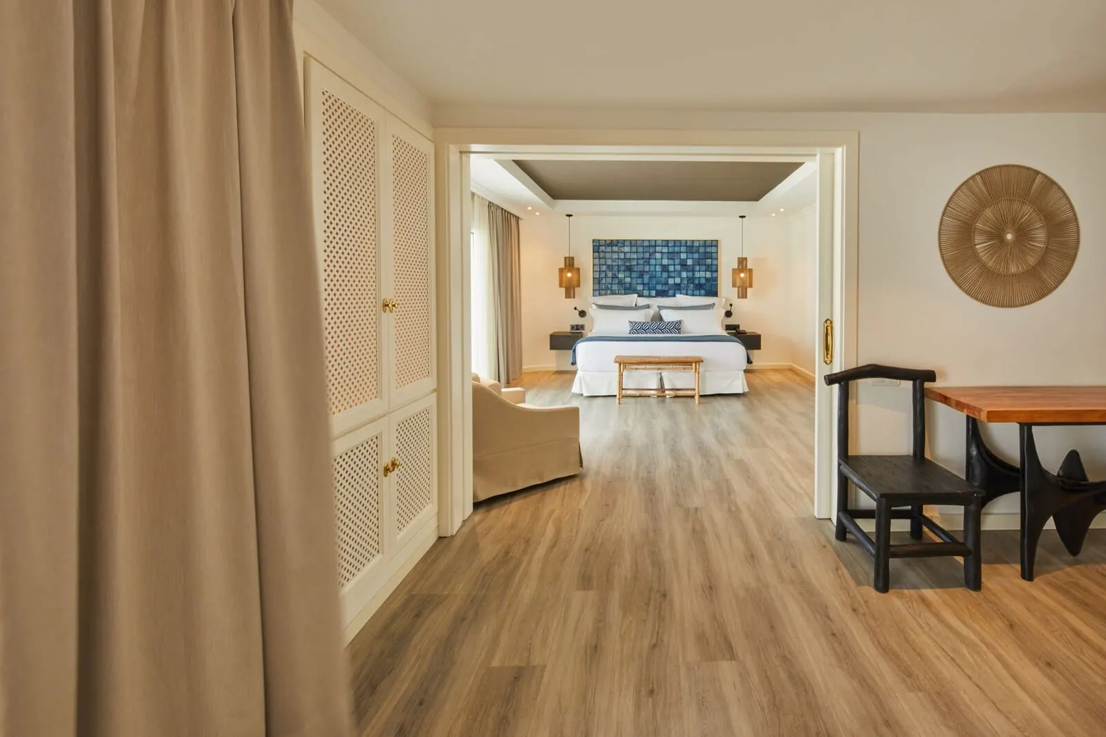 Hyatt Ziva Jardín Tropical Tenerife: A hotel room with a wooden floor, a bed with a blue and white headboard, a wooden bench