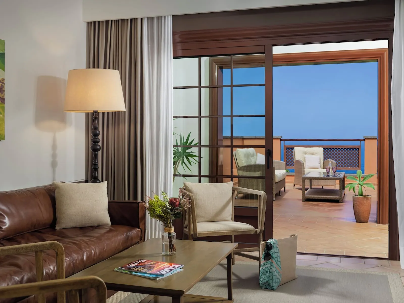 Hacienda del Conde Meliá Collection Golf & Spa: A hotel room with a leather sofa, a coffee table with magazines, a vase with flowers