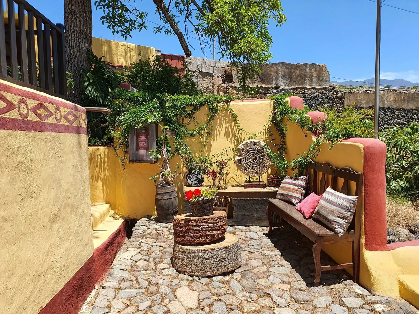 Hotel Rural La Raya 1866: A courtyard with a stone floor, a wooden bench, a round table, and potted plants