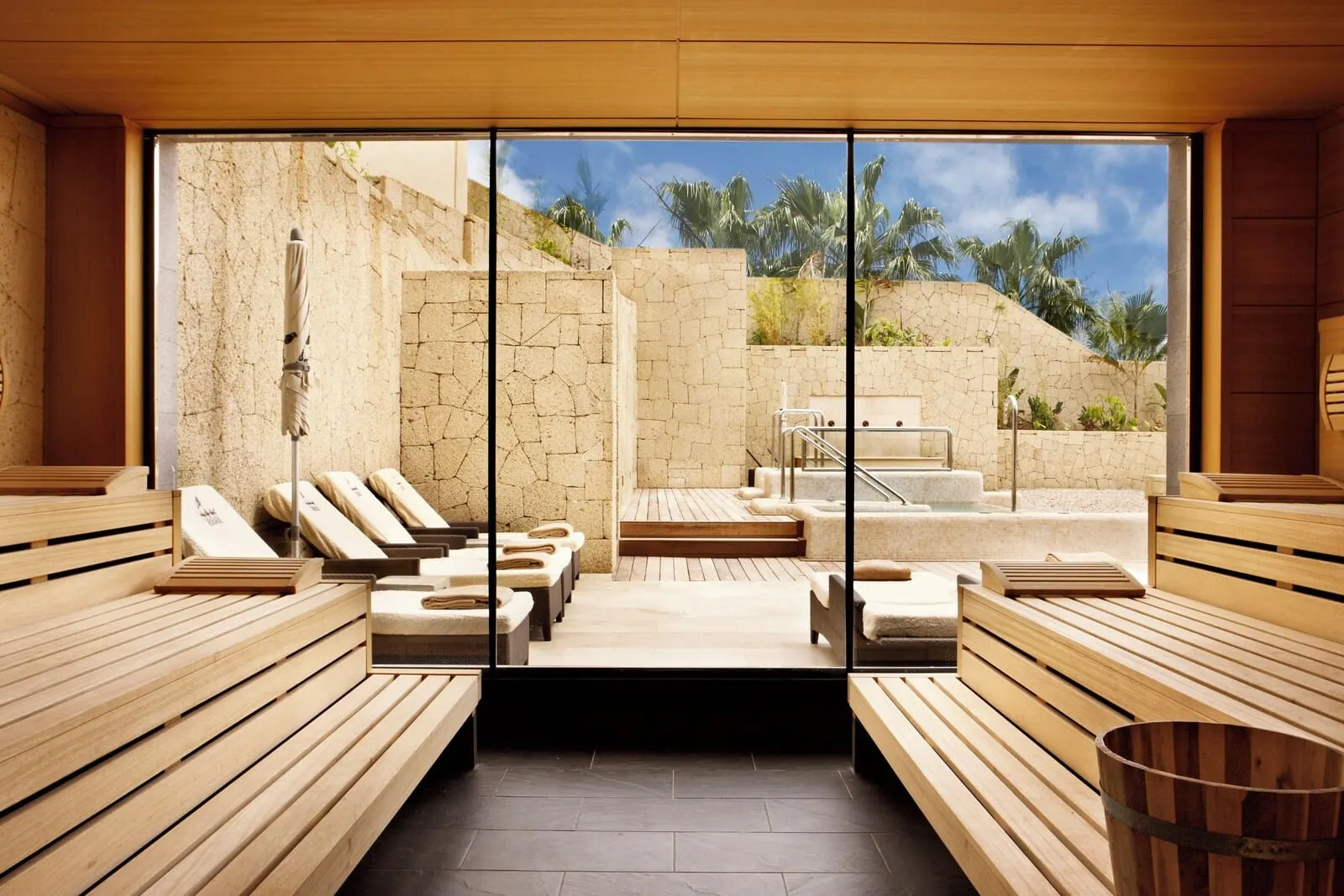 Bahía del Duque: A sauna with wooden benches and a stone wall backdrop