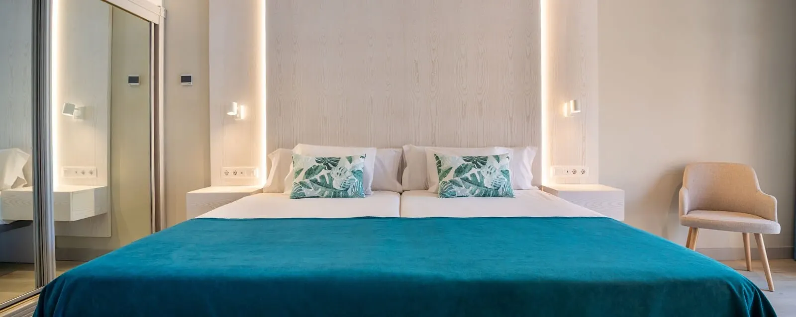Villa Mandi Golf Resort: A modern hotel room with a large bed, two bedside tables, a chair, and a mirror