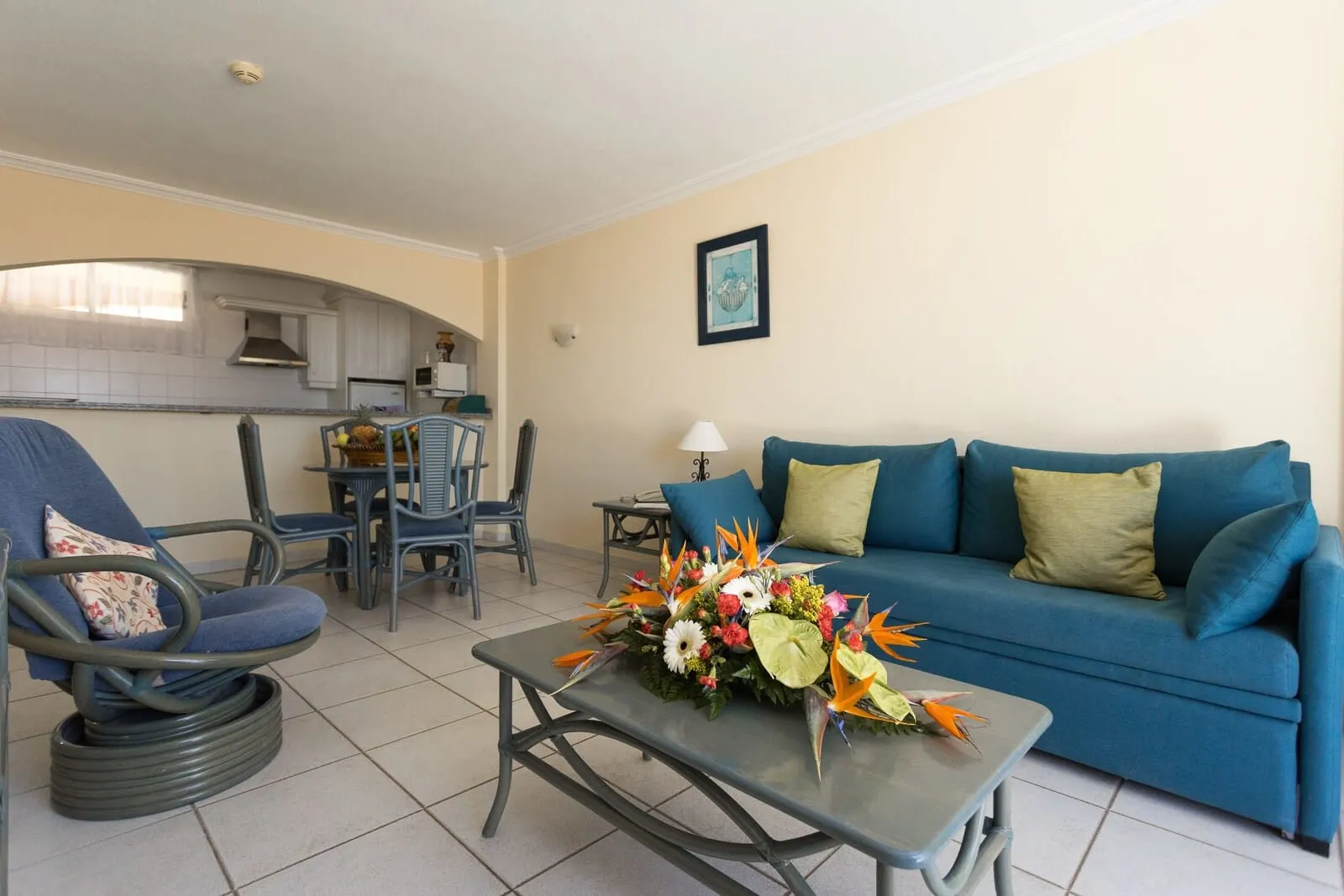 El Marqués Palace: A living room with a blue sofa, a chair, a coffee table with a floral arrangement