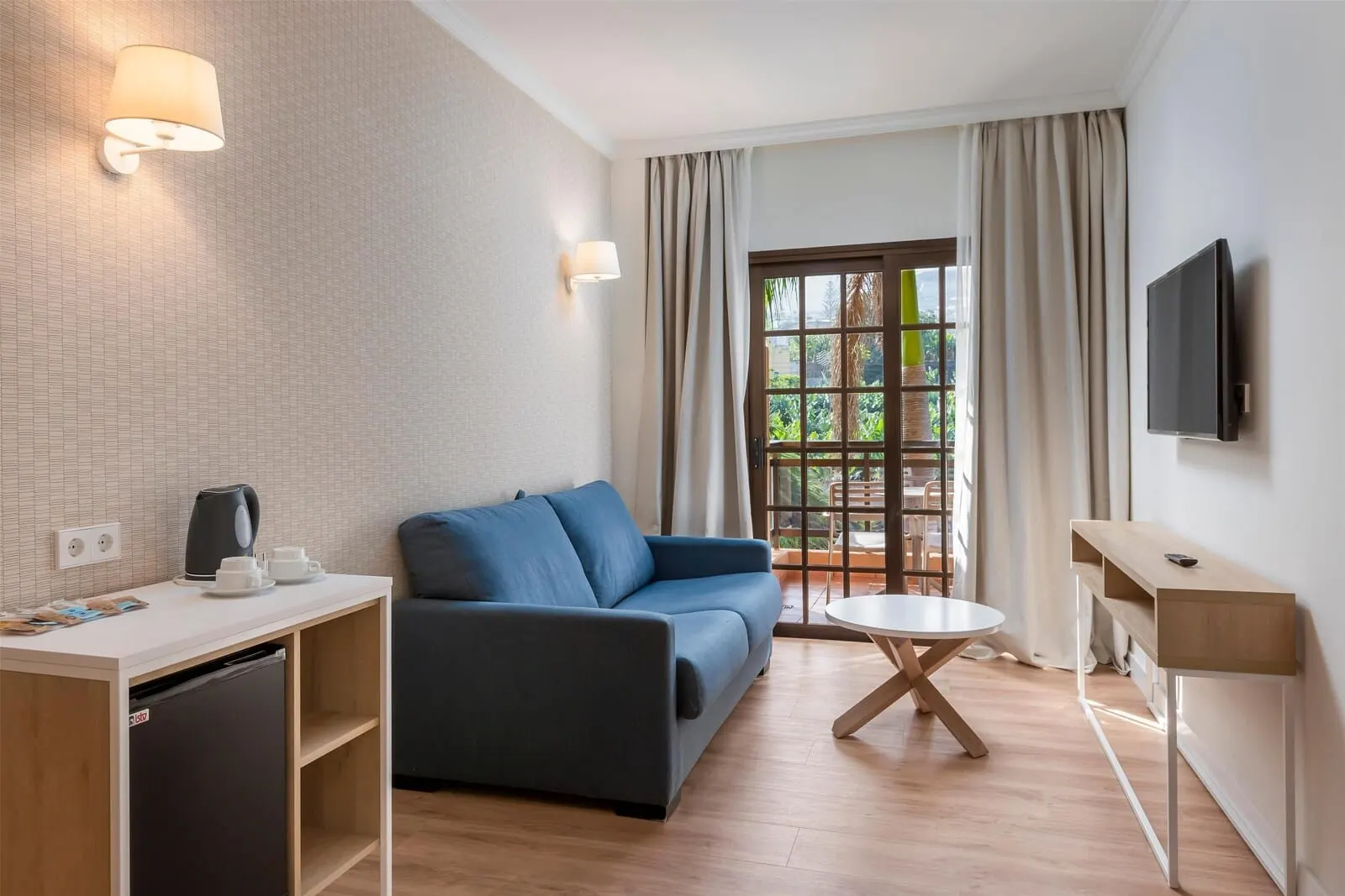 AluaSoul Orotava Valley: A modern hotel room with a sofa, a small dining table, a TV mounted on the wall