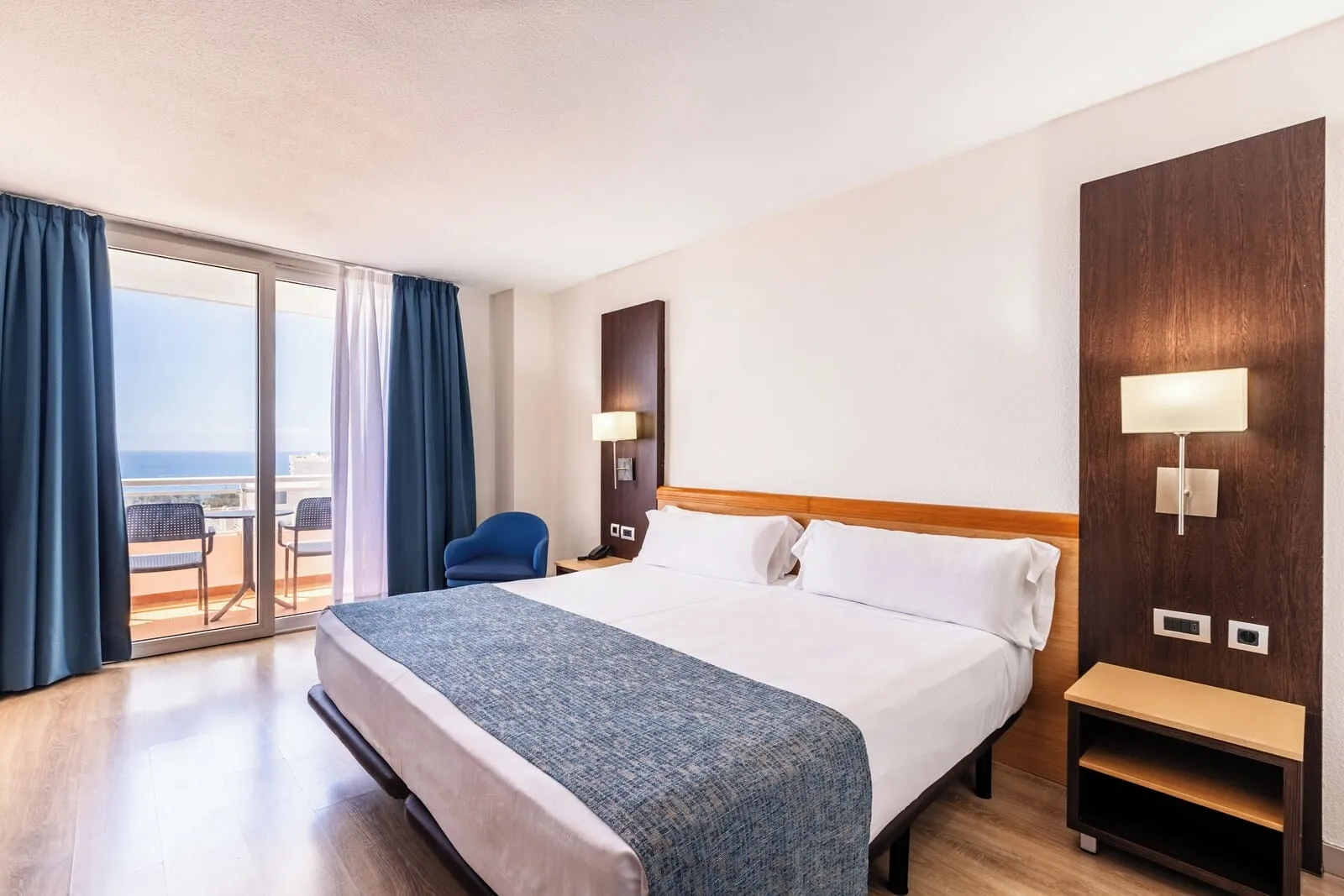 Catalonia Oro Negro: A hotel room with a large bed, a wooden nightstand, a desk