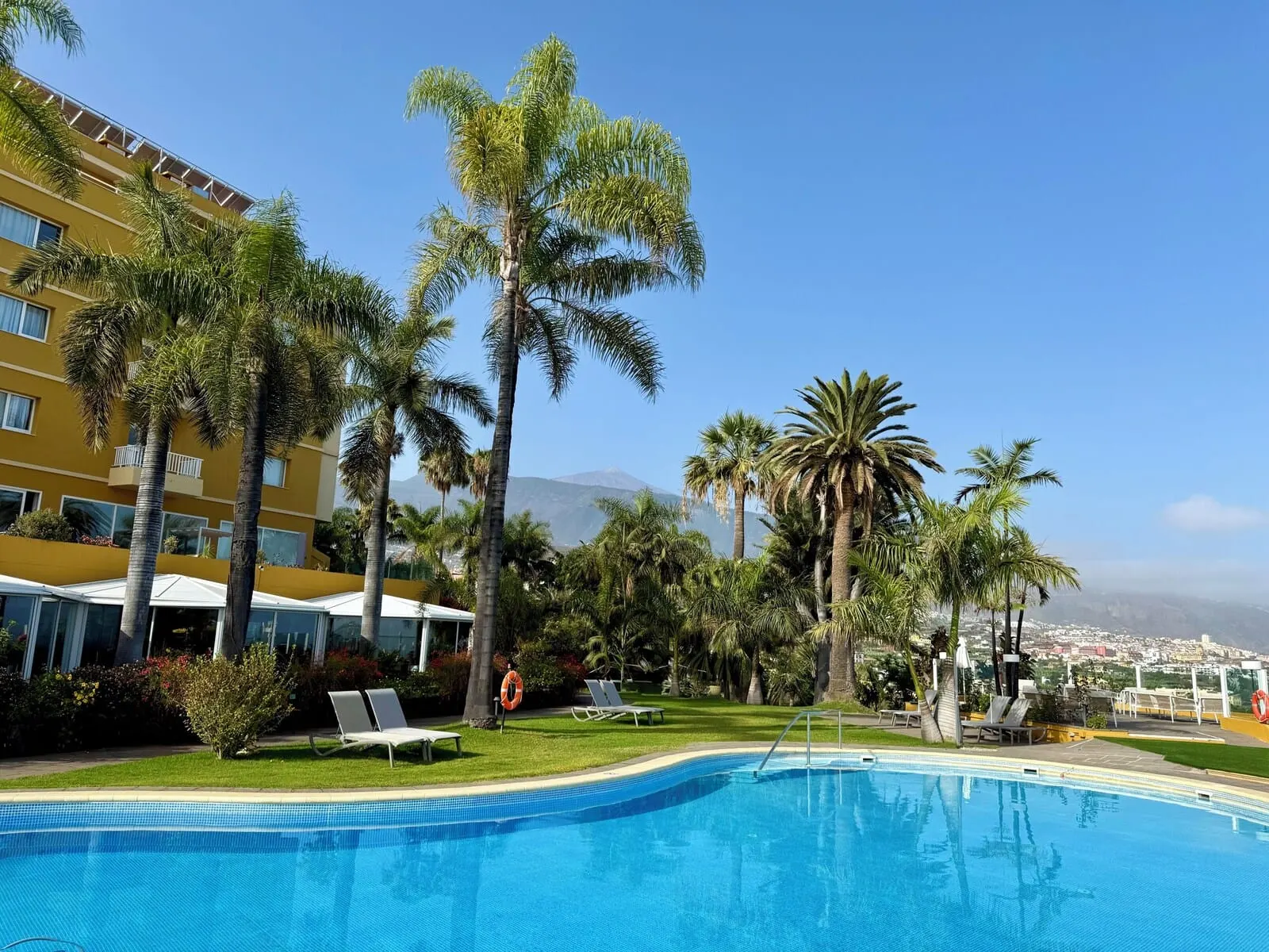 Hotel Tigaiga: A hotel pool with palm trees, a lifebuoy, and a mountain in the background
