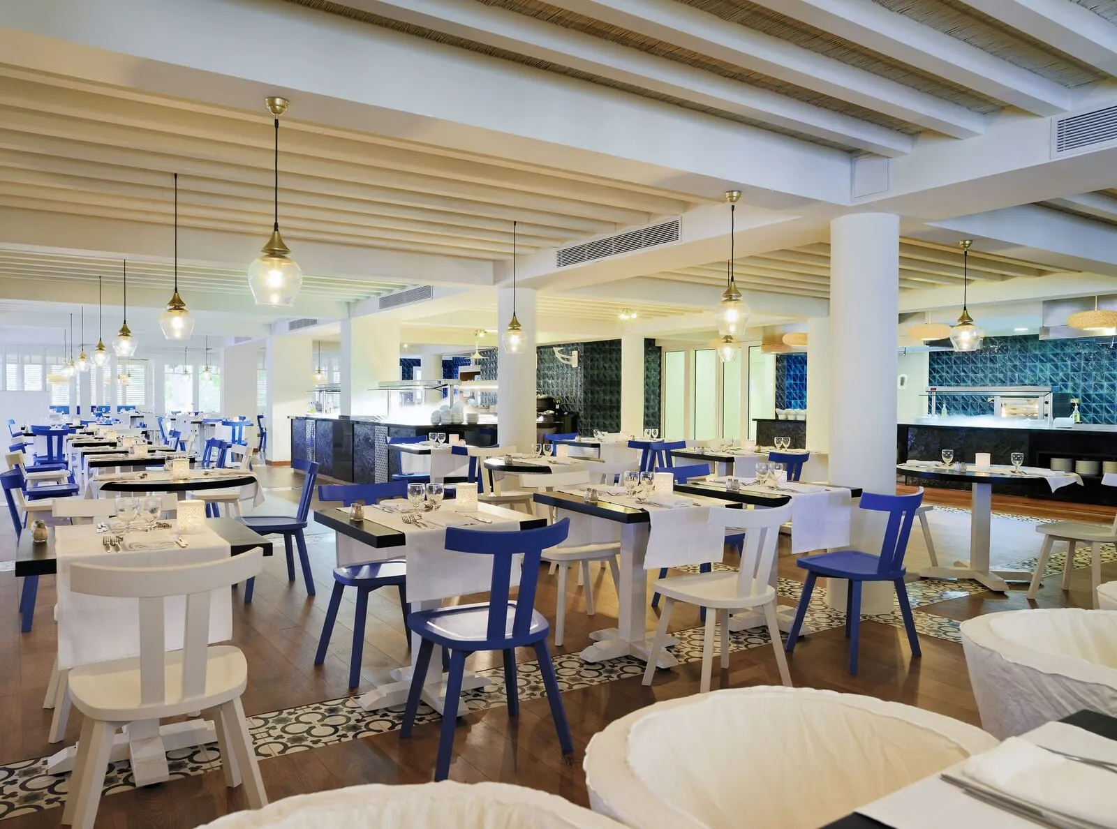 H10 Big Sur: A restaurant with multiple dining tables and chairs, a kitchen area