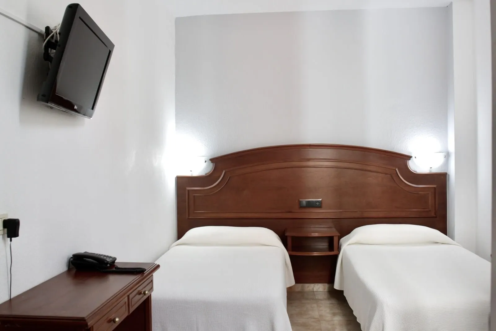 Hotel Tropical: A hotel room with a wooden headboard, two beds, a bedside table with a phone
