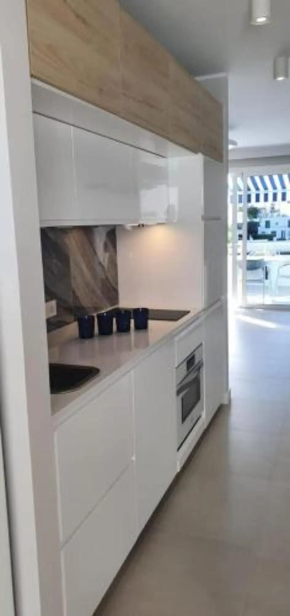 Malibu Park: A modern kitchen with white cabinetry, a wooden countertop, and a built-in oven