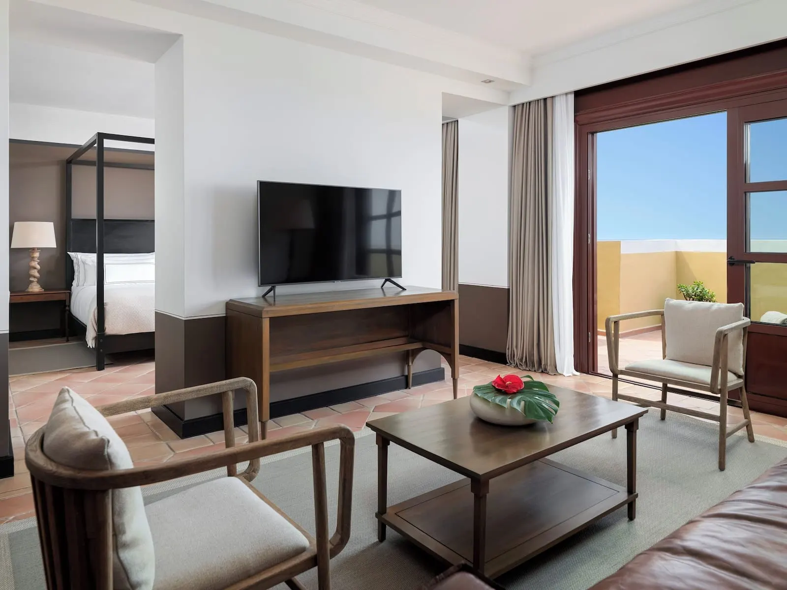 Hacienda del Conde Meliá Collection Golf & Spa: A hotel room with a bed, a TV, a coffee table, two chairs, a small table with a plant