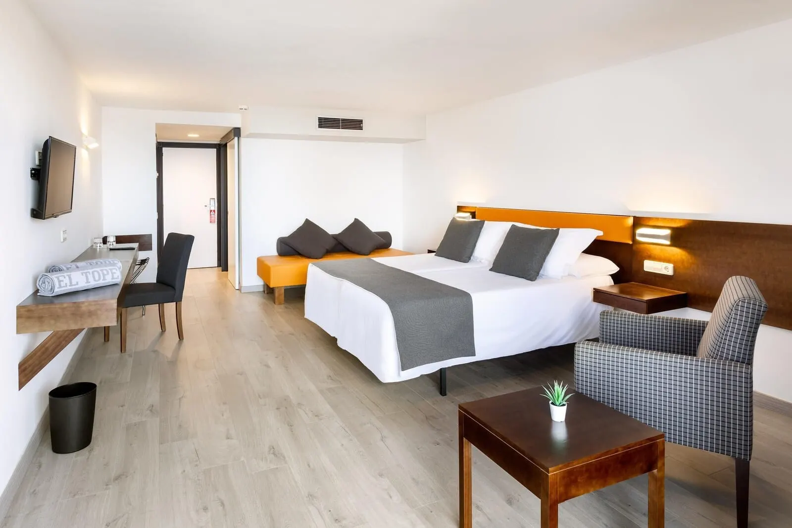 Hotel Atlantic El Tope: A hotel room with a bed, bedside table, chair, desk, and a TV mounted on the wall