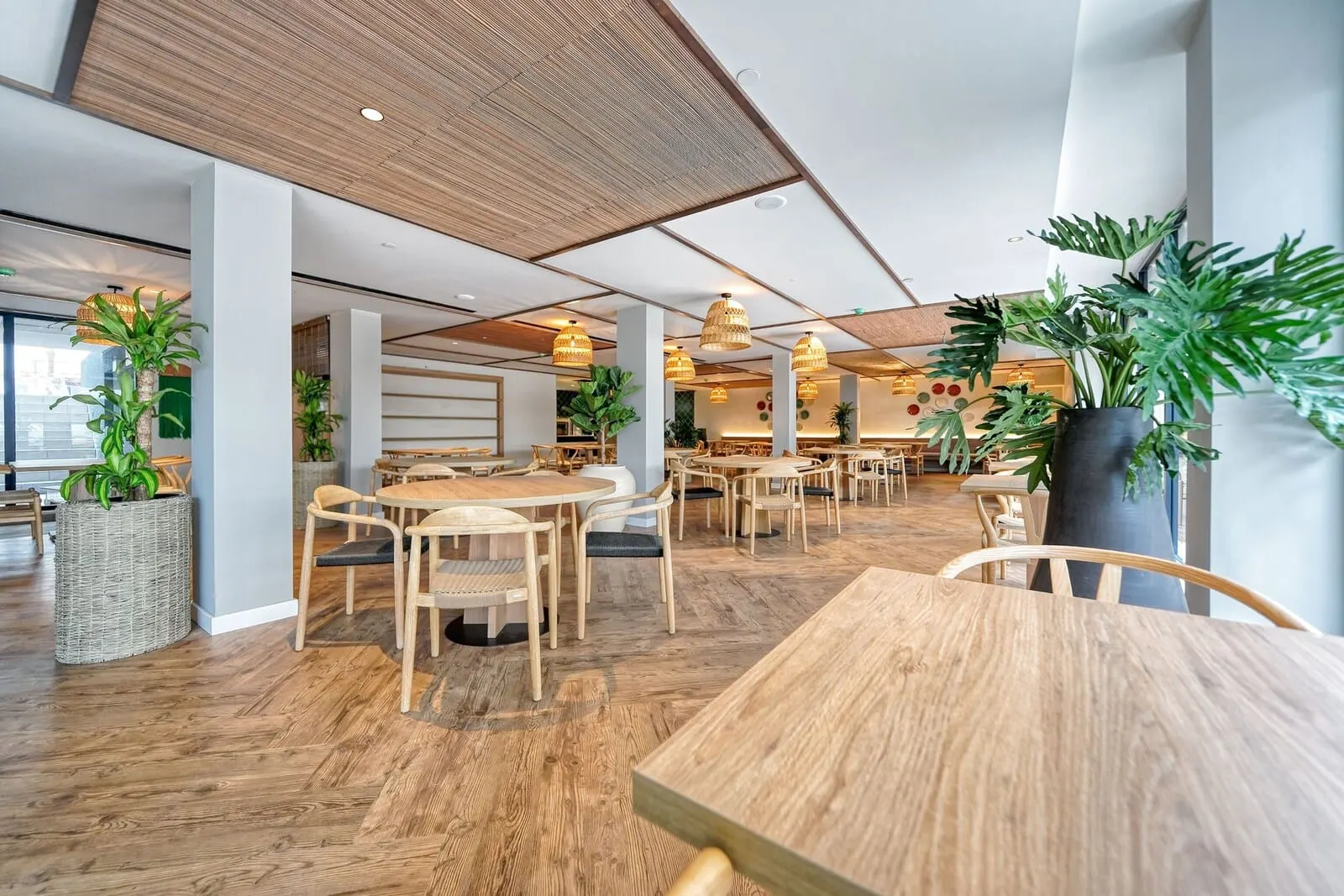 HOVIMA Suites Costa Adeje: A modern dining area with wooden tables and chairs, large potted plants