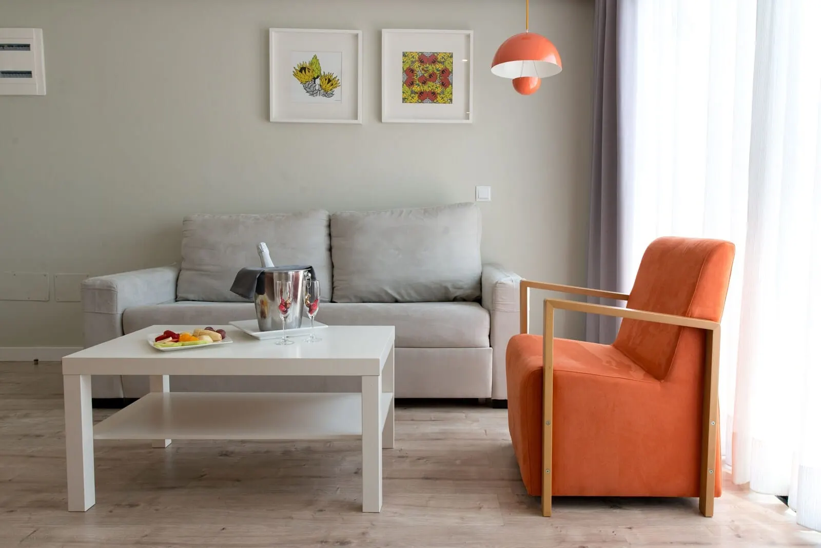Vanilla Garden Boutique Hotel: A modern living room with a grey sofa, an orange armchair, a white coffee table