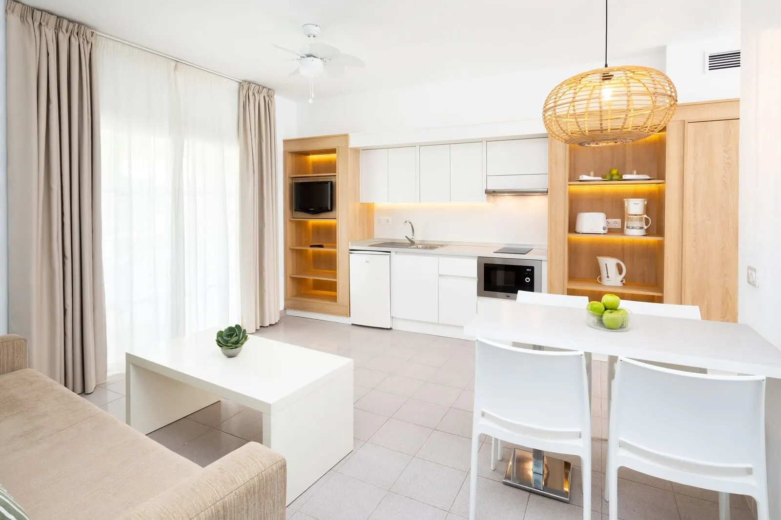 Los Olivos Beach Resort: A modern kitchen with white cabinets, a dining area with a white table and chairs