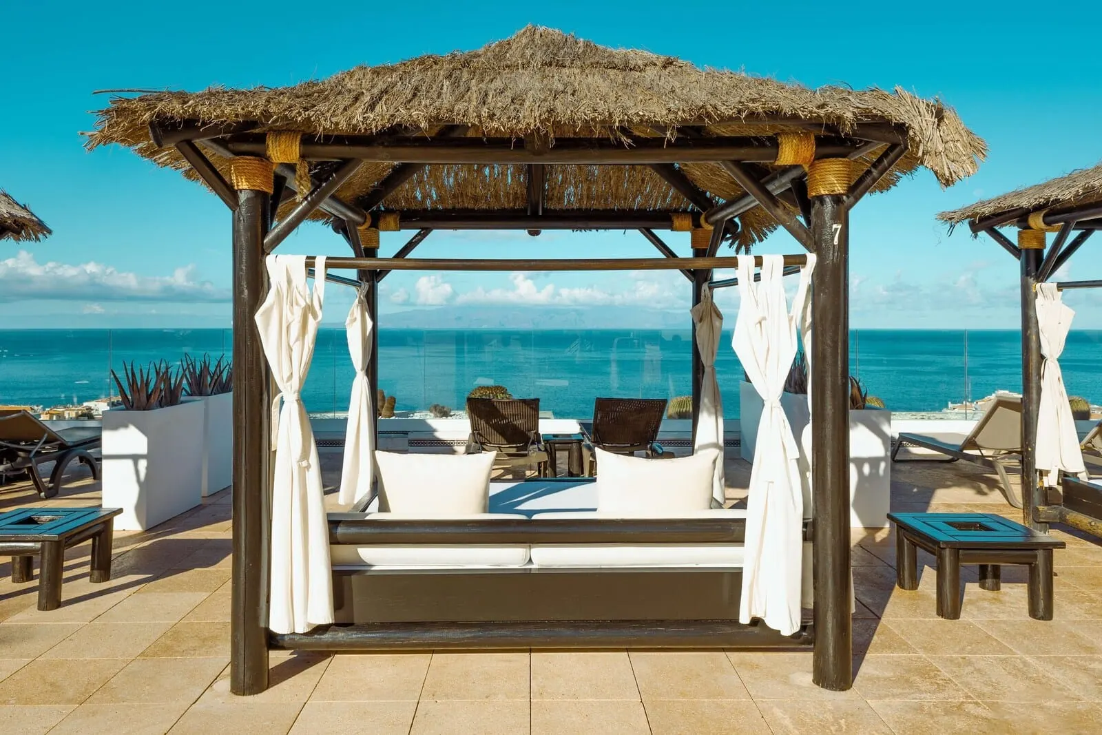 Landmar Costa Los Gigantes: A beach cabana with a thatched roof, white curtains