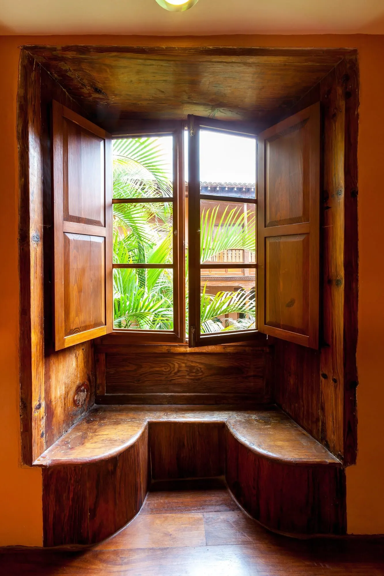Hotel La Quinta Roja: A wooden bench with a window overlooking a garden