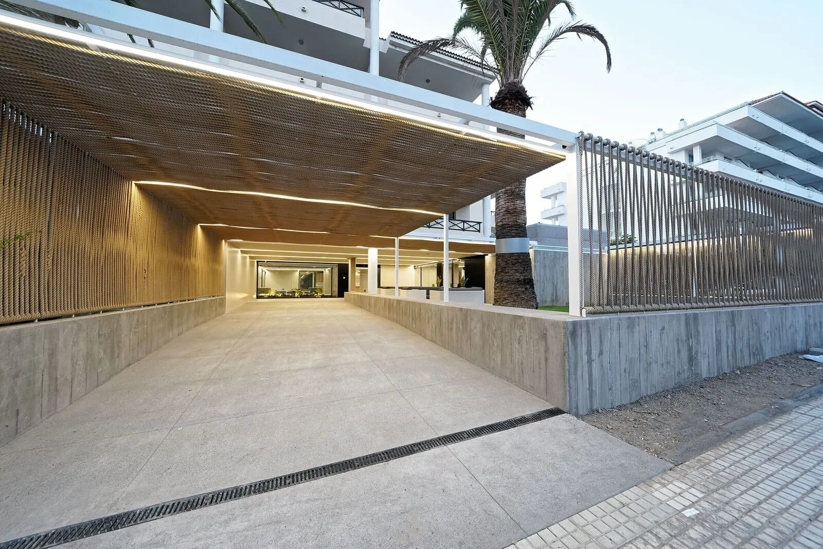 Hotel Parque La Paz: A modern building with a covered walkway, a palm tree