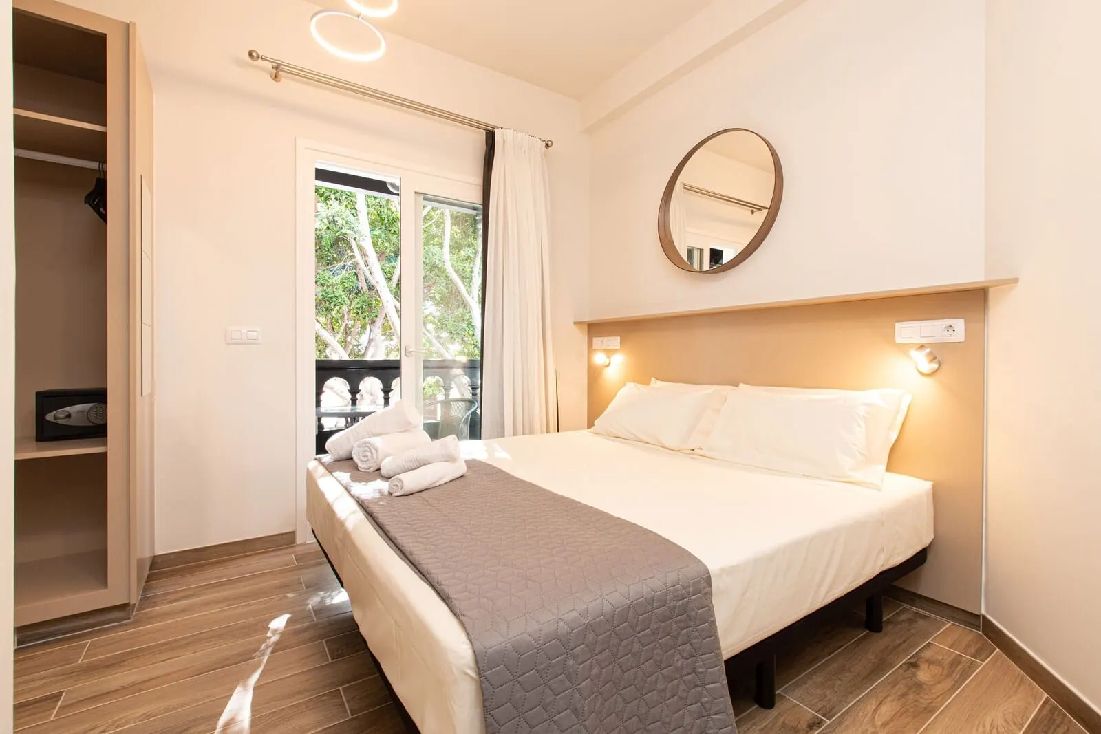 Suncanarias Hotel Adeje Plaza: A hotel room with a bed, a mirror, a window with curtains, and a view of trees outside