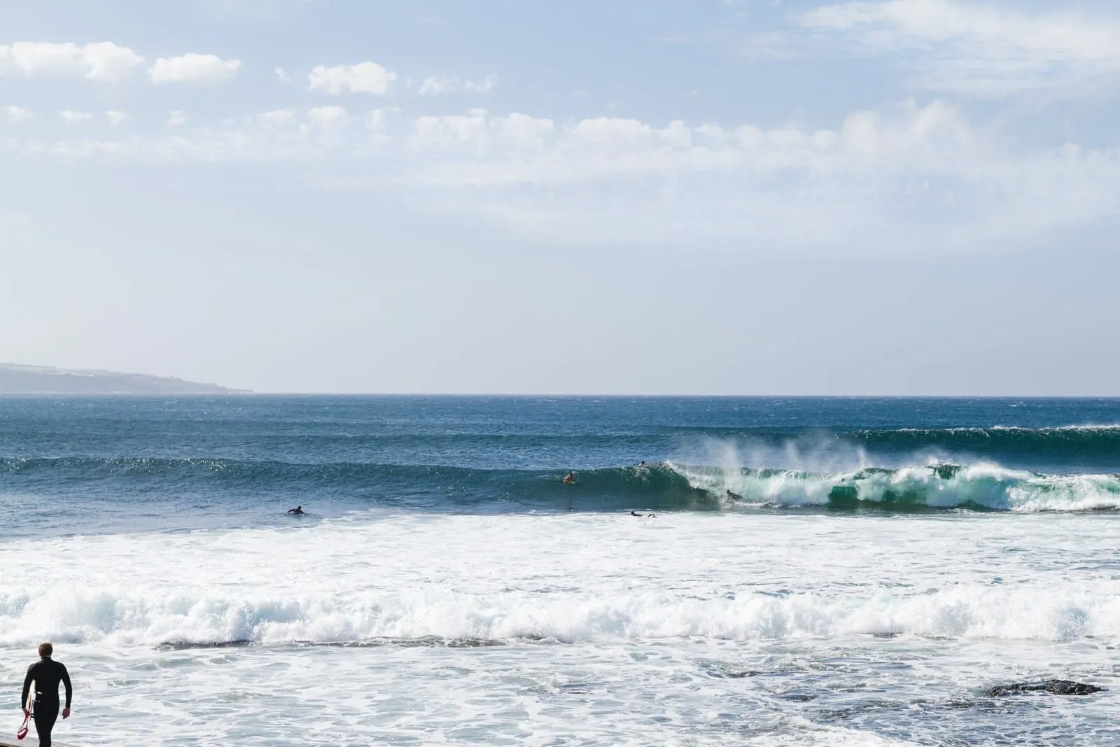 Océano Health Spa Hotel: A beach with waves and a person in a wetsuit walking
