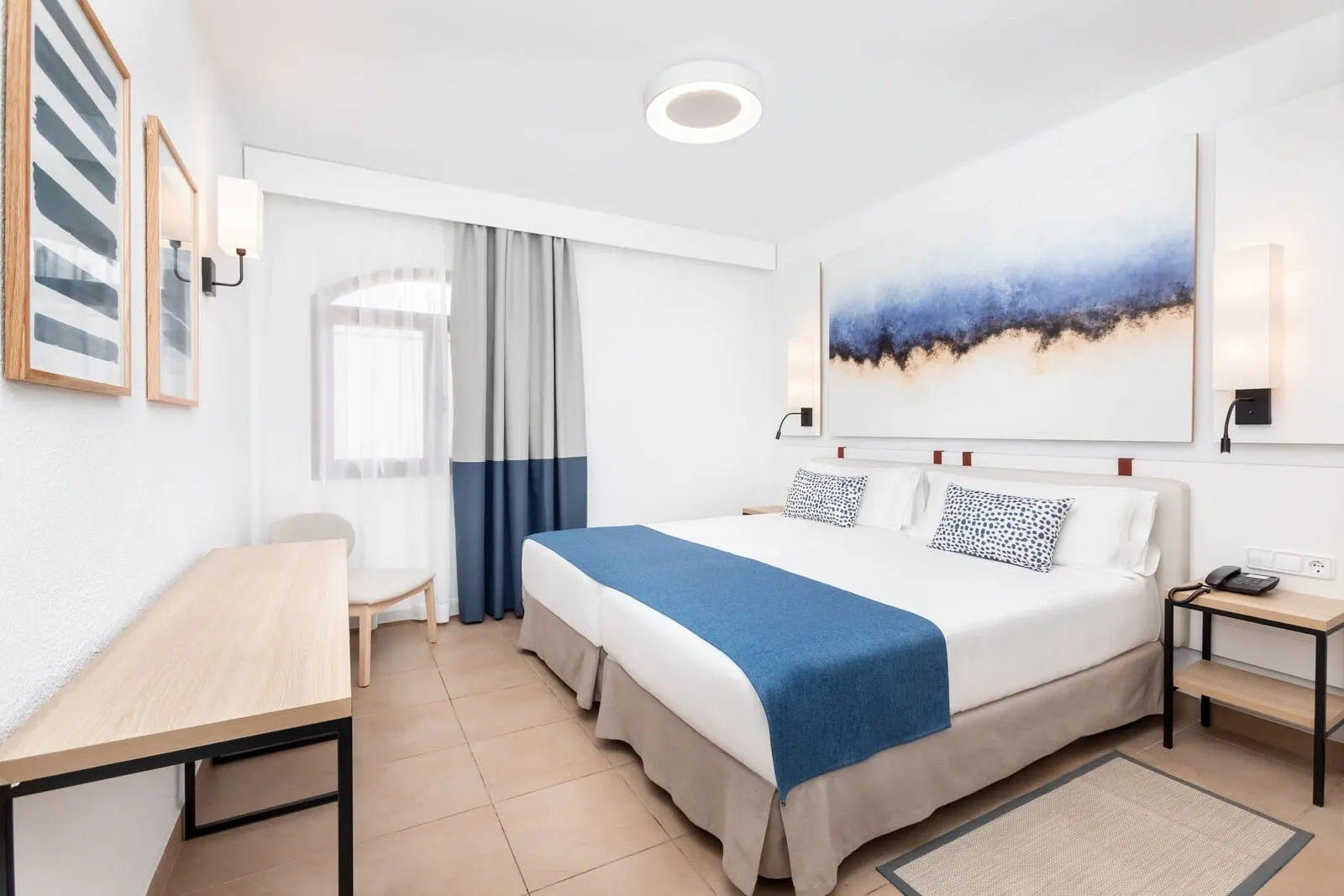 HD Parque Cristóbal Tenerife: A modern hotel room with a large bed, a desk, a chair, and a painting on the wall
