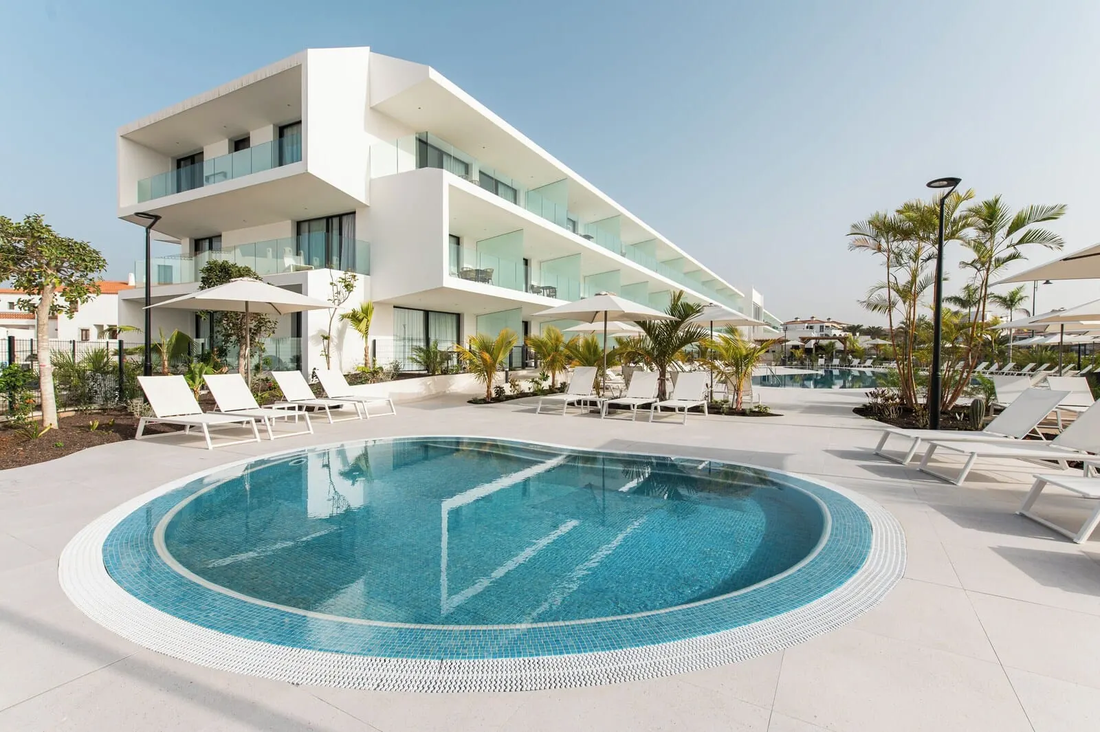 Amarilla Golf Residences: A modern hotel with a swimming pool, sun loungers, and a clear blue sky