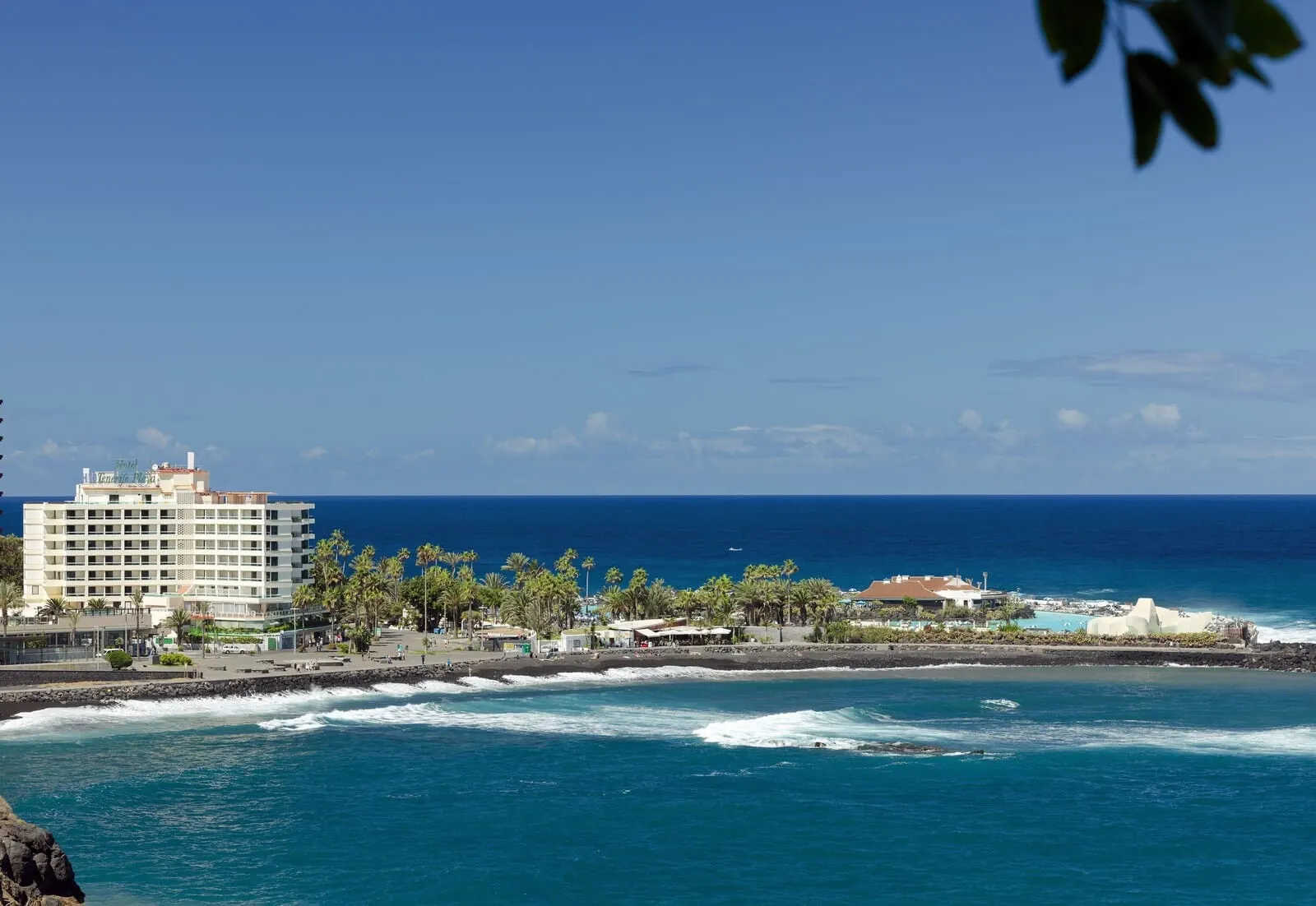 H10 Tenerife Playa: A coastal hotel with a view of the ocean, a beach, and a rocky shoreline