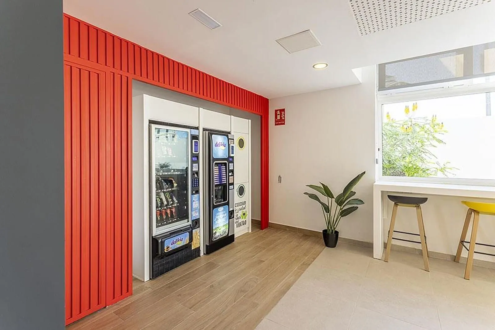 Sholeo Lodges Los Gigantes: A room with a red wall, a window with a view of greenery, and a vending machine