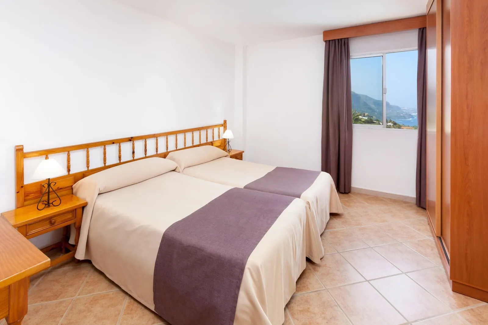 Hotel Panorámica Garden: A double bed with a wooden headboard, two bedside tables with lamps