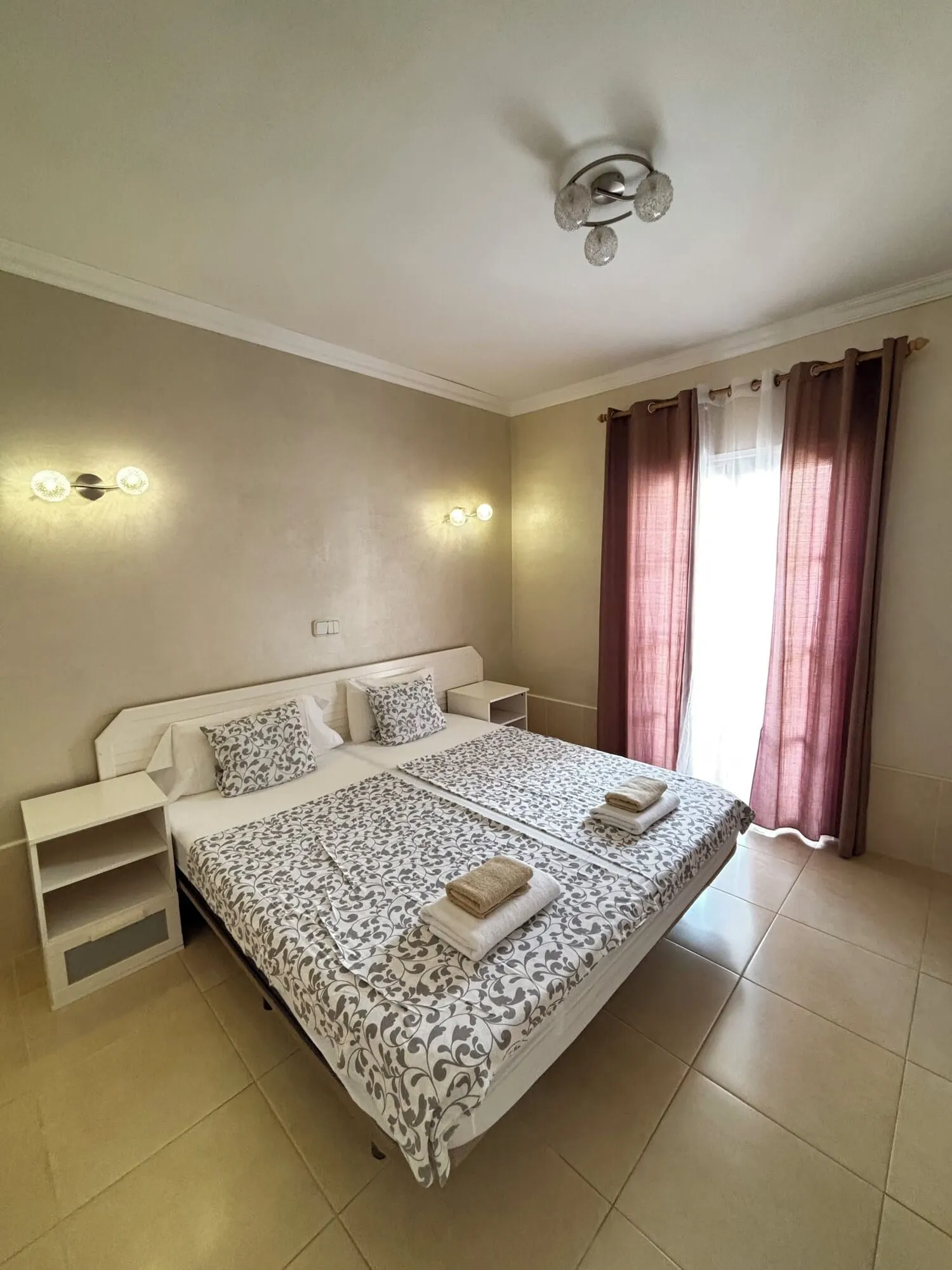 Yucca Park Aparthotel: A bedroom with a bed, bedside tables, a ceiling fan, and curtains