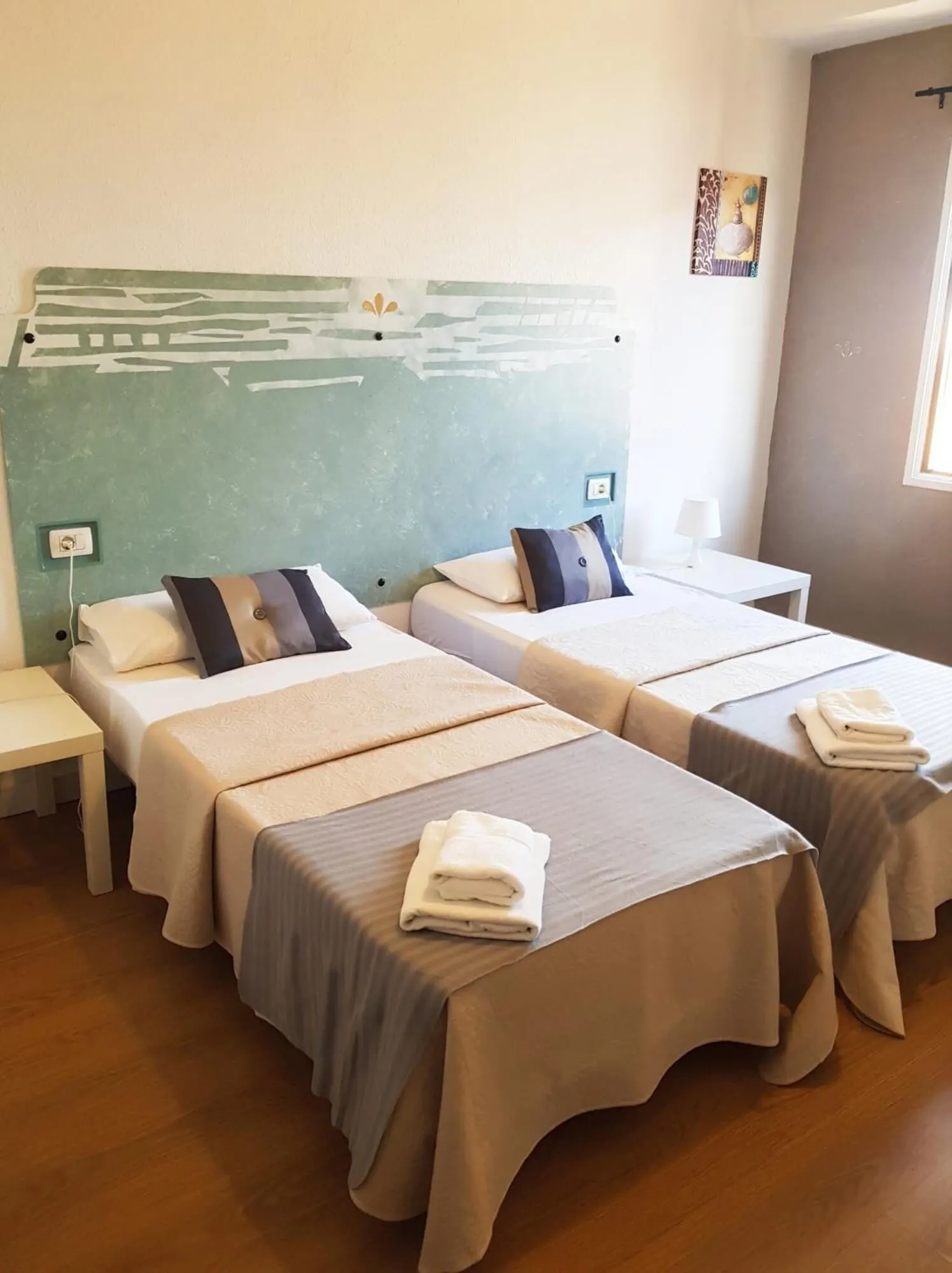 Nuevo Hotel Horizonte: A hotel room with two beds, each with a headboard, bedside tables, and folded towels